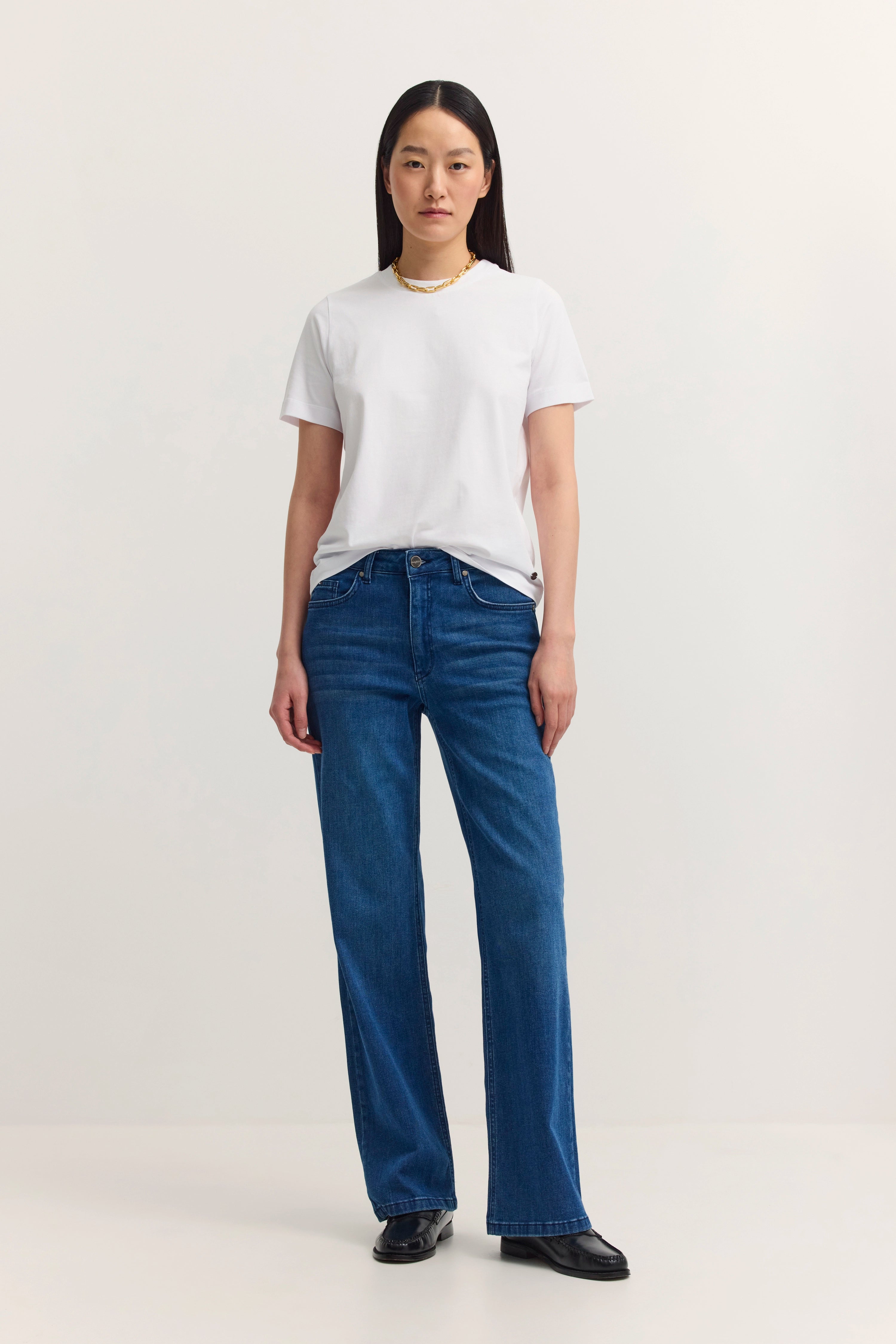 Model in weißem T-Shirt und blauer Jeans von bugatti, frontal stehend.