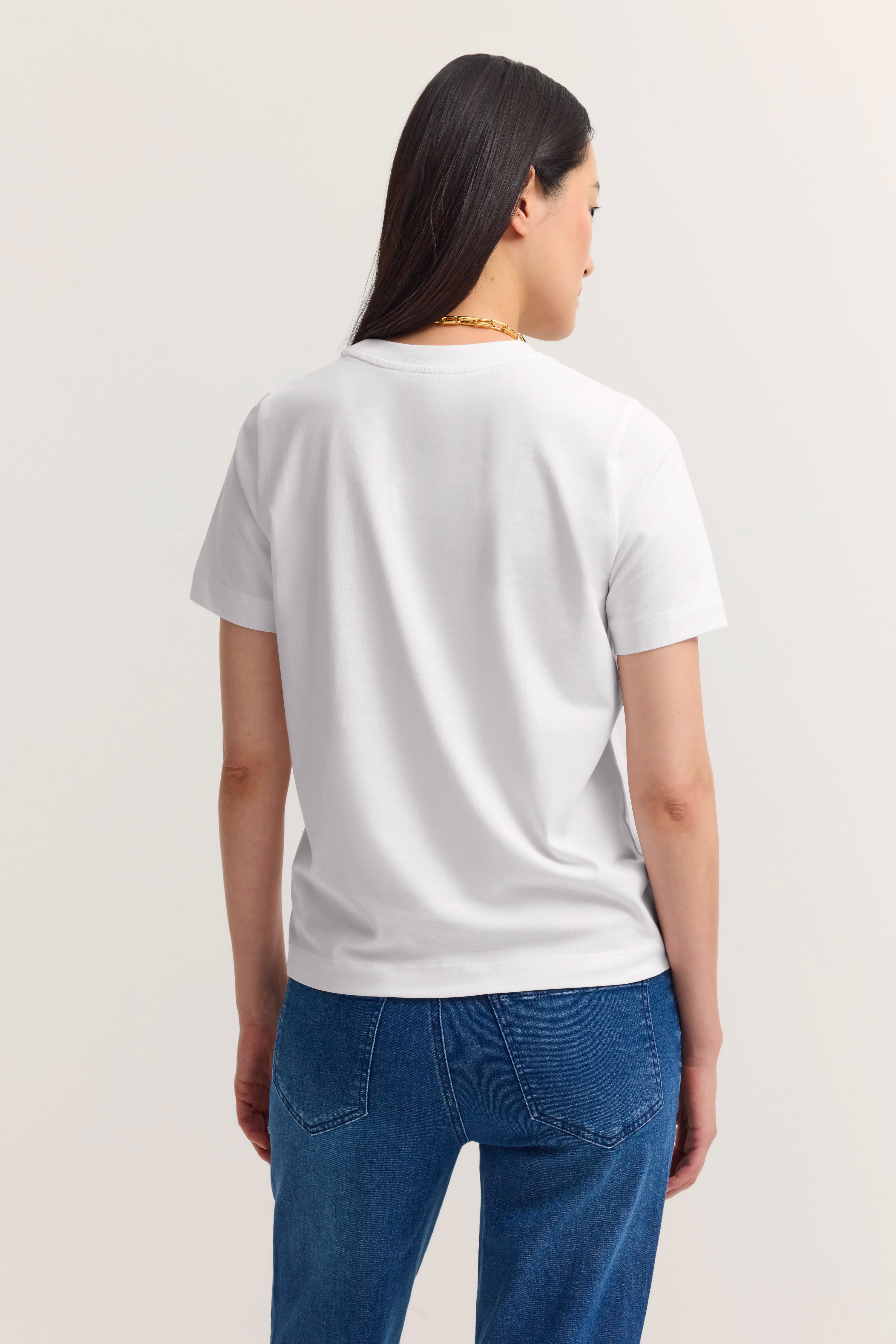 Weißes T-Shirt und blaue Jeans. Model von hinten.