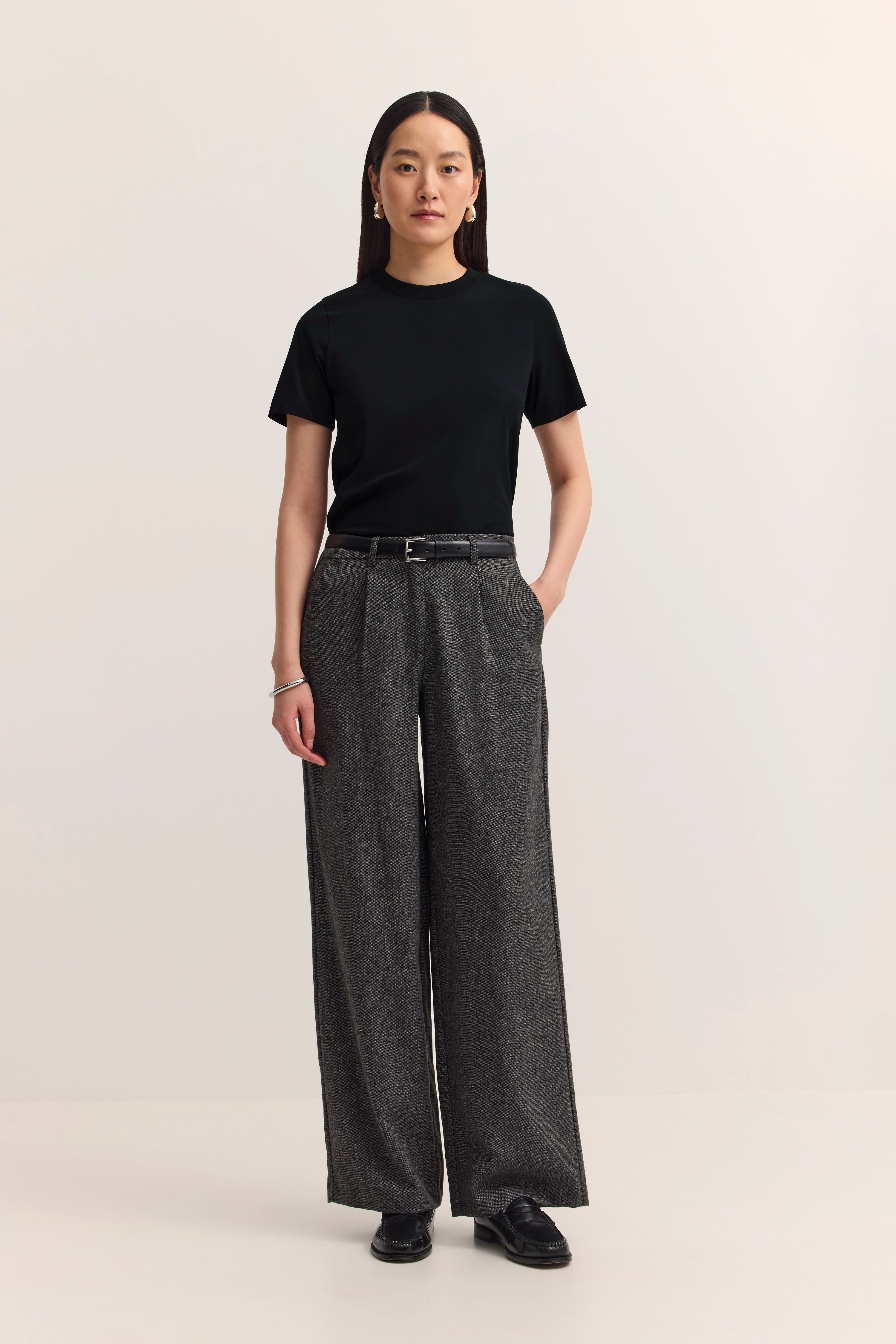 Model in schwarzem T-Shirt und grauer, weiter Hose von bugatti, steht frontal, entspannt.