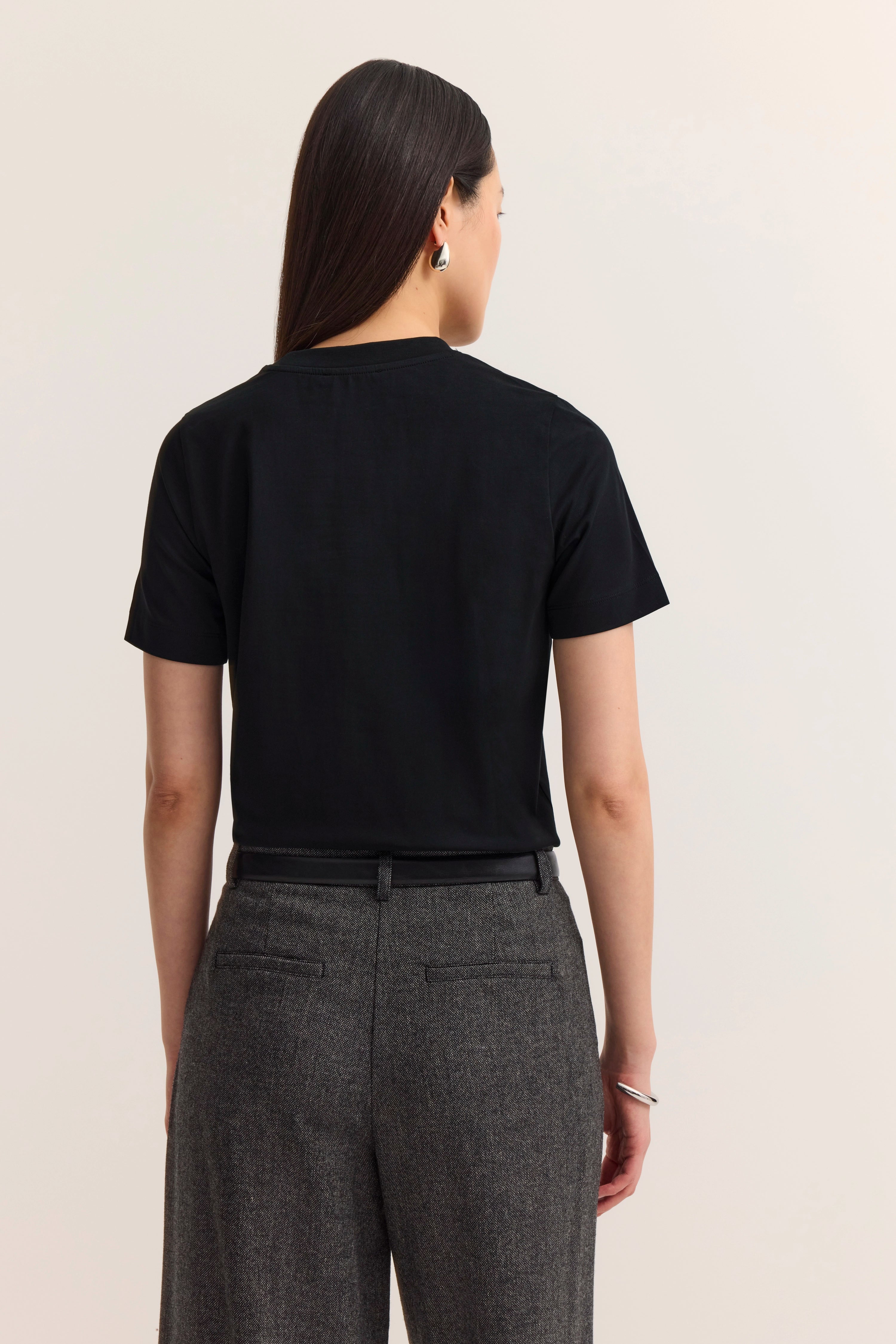 Schwarzes T-Shirt und graue Hose, Model von hinten.