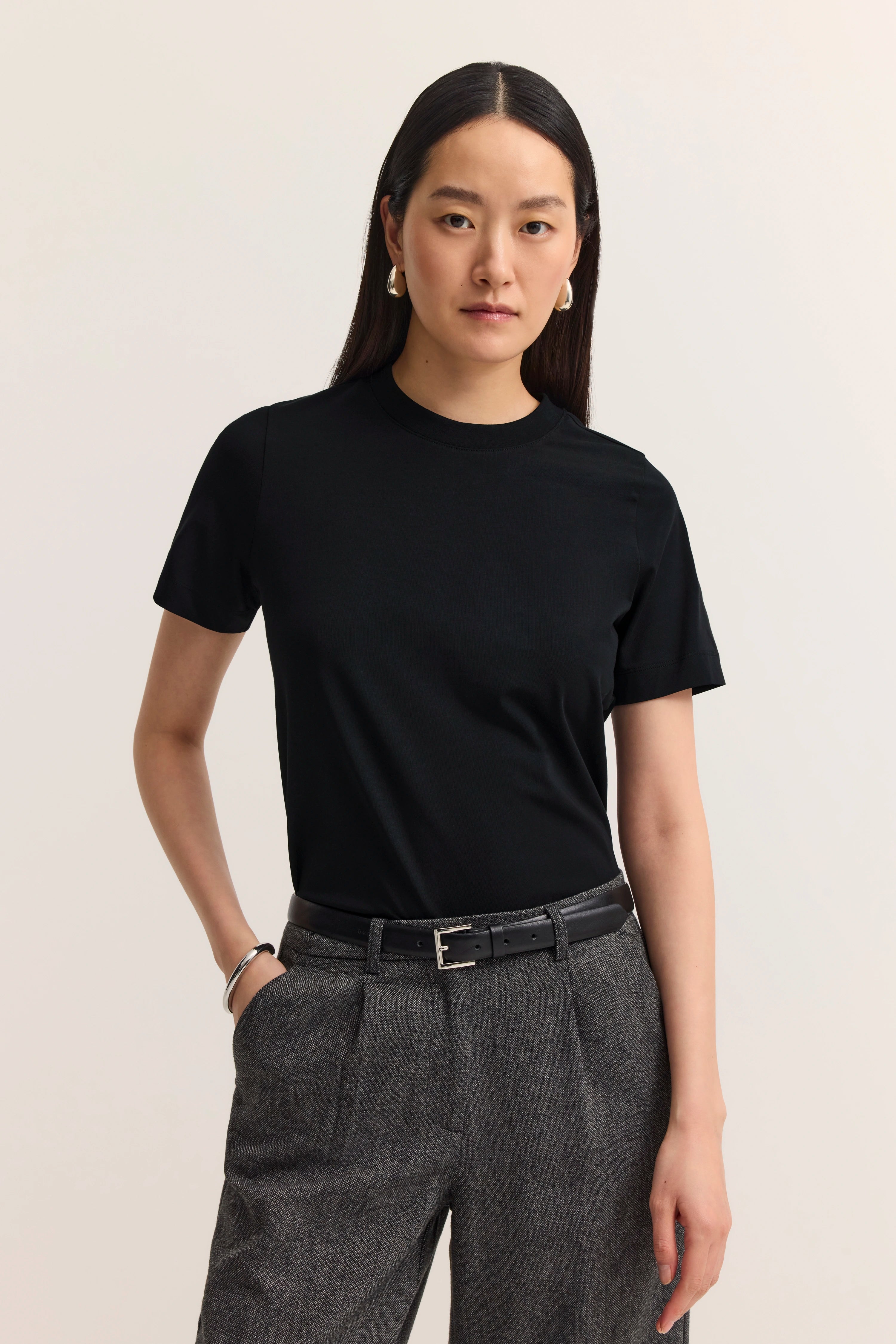 Schwarzes T-Shirt und graue Hose von bugatti, Modelbild, Posen mit Händen in den Hosentaschen.