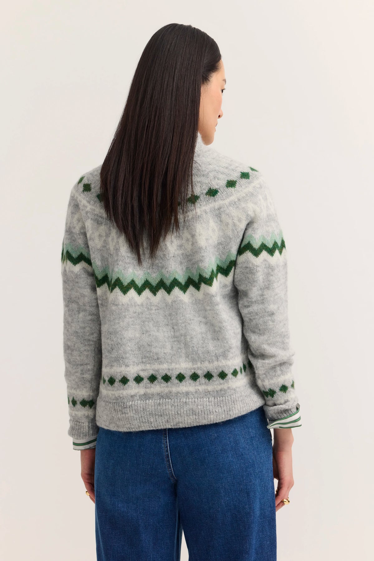 Grauer Strickpullover mit grünem Muster, Modell von hinten, lässiger Stil, kombiniert mit blauer Jeans.