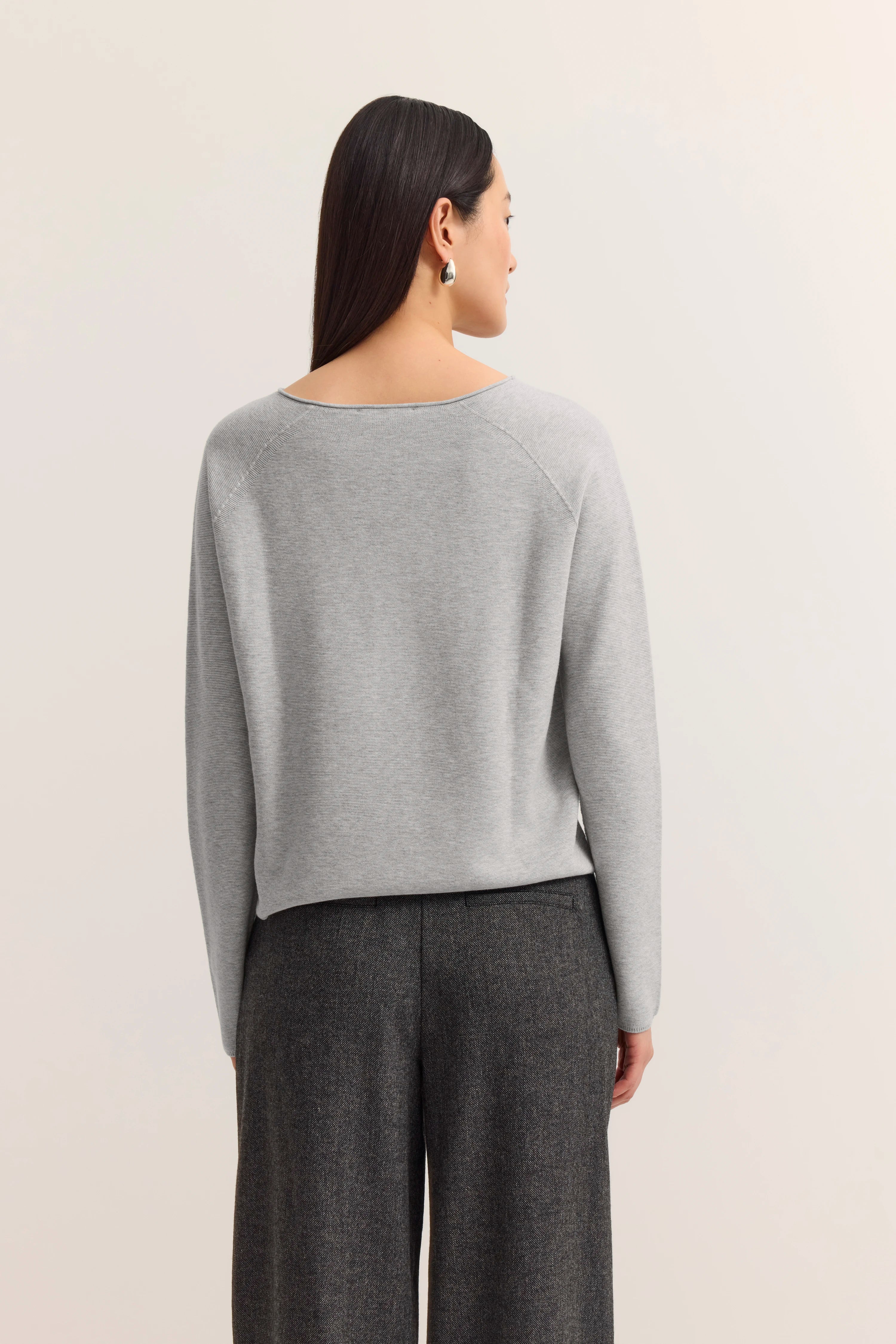 Grauer Pullover, graue Hose, Rückansicht, legeres Modelbild, aufrecht stehend.