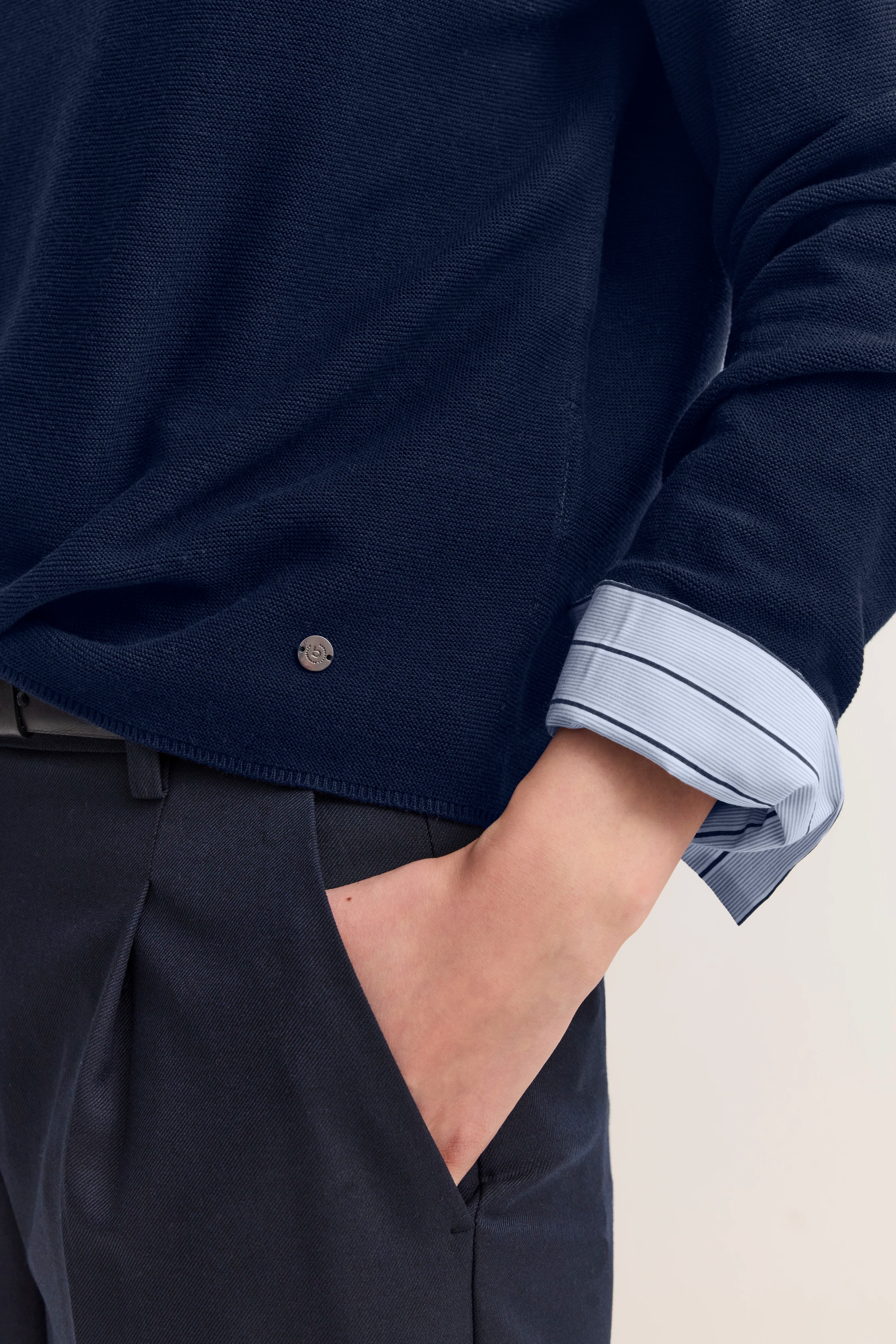 Bugatti Modelbild: Dunkelblauer Pullover über gestreiftem Hemd, lässige Pose von hinten.