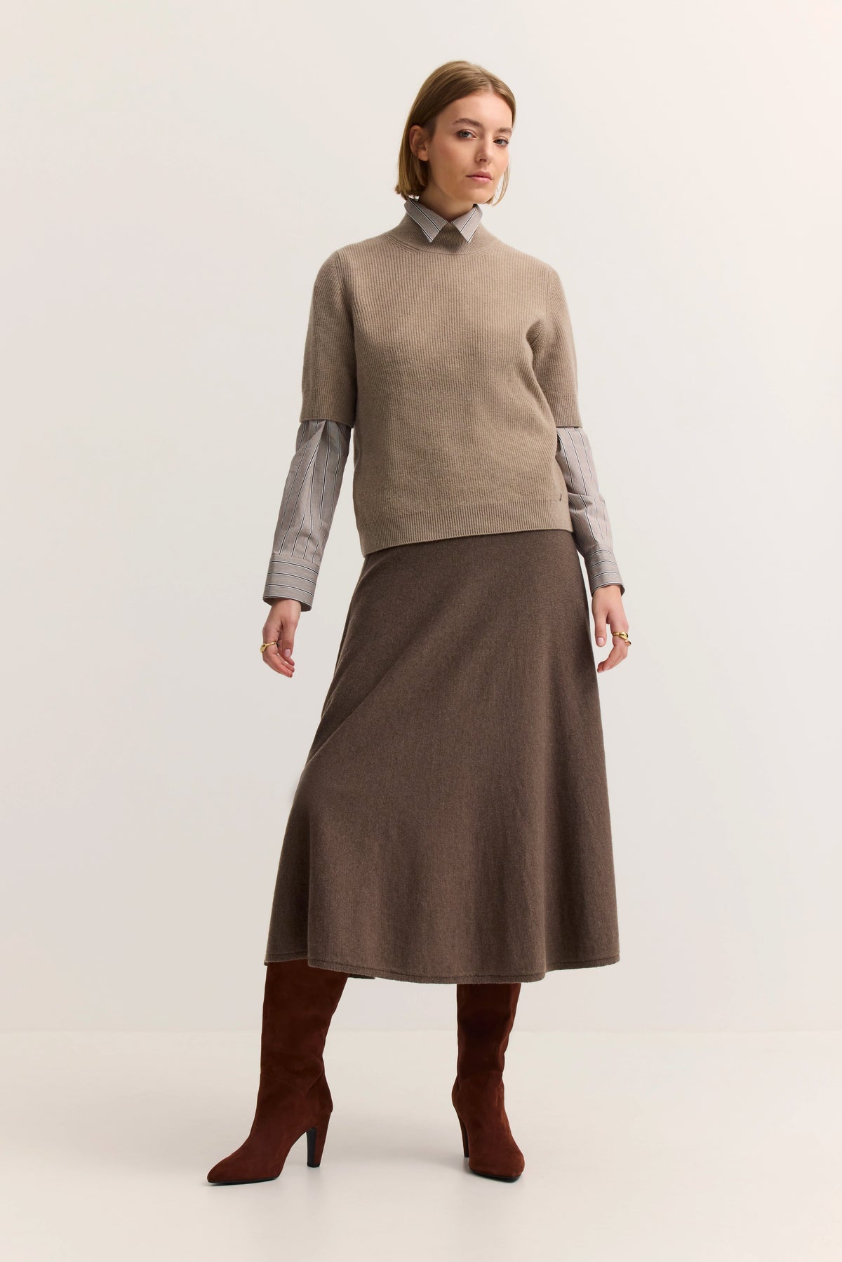 Model in beige Pullover, braunem Rock, rotbraunen Stiefeln