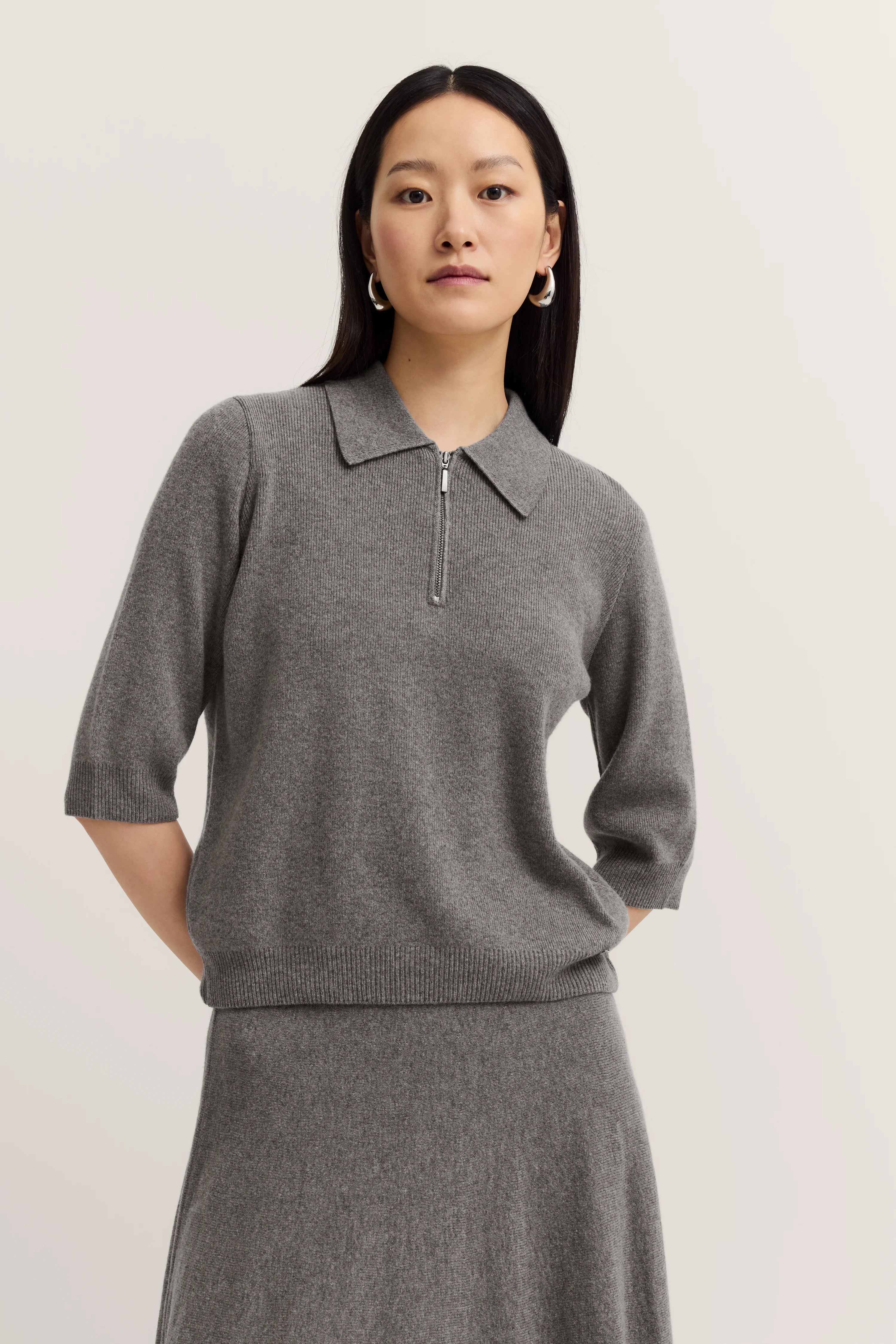 Graues Polo-Kleid mit Reißverschluss, Halbarm, Modelbild, entspanntes Posing.