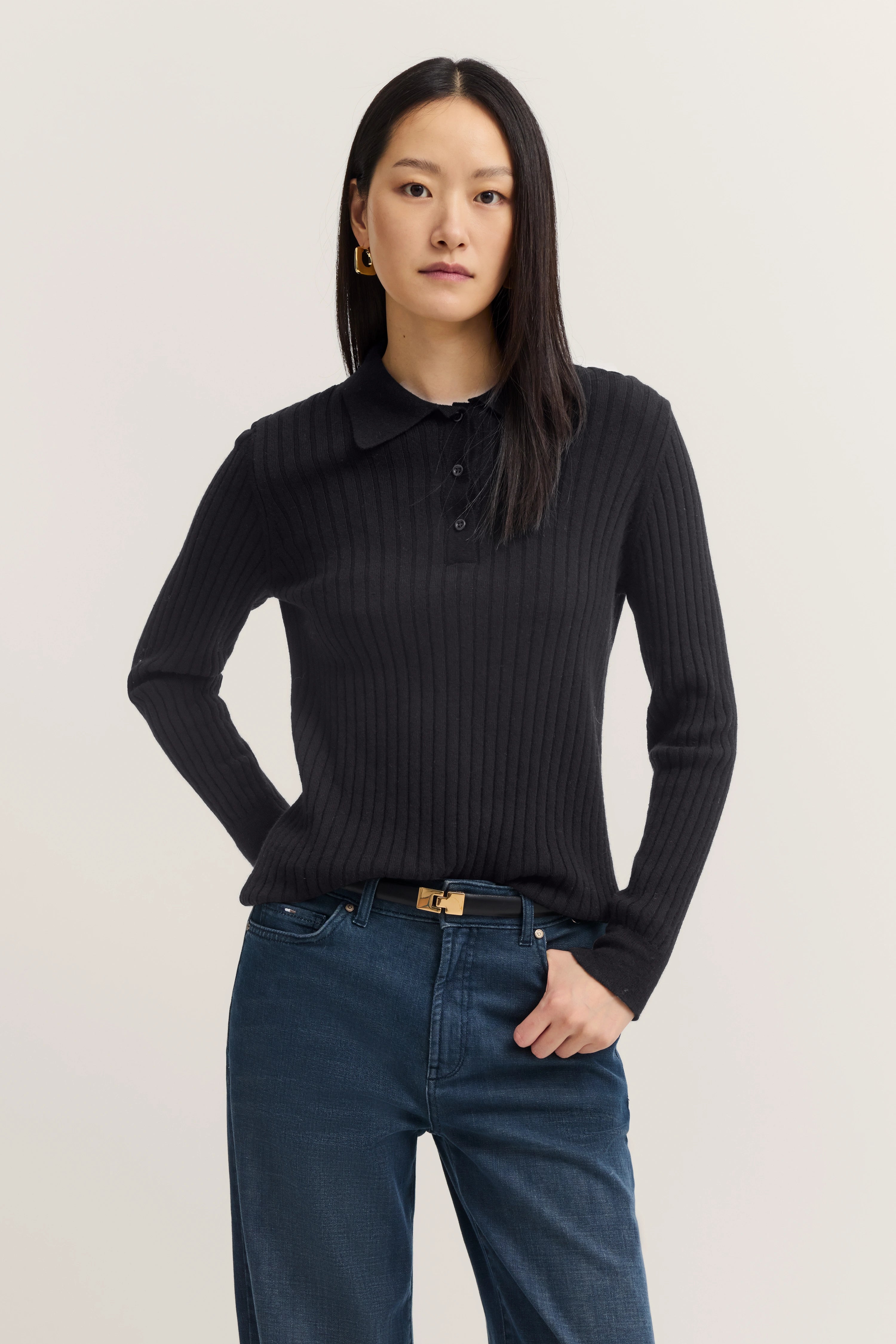 Schwarzer gerippter bugatti Pullover und blaue Jeans, Modelbild mit legerem Stand.