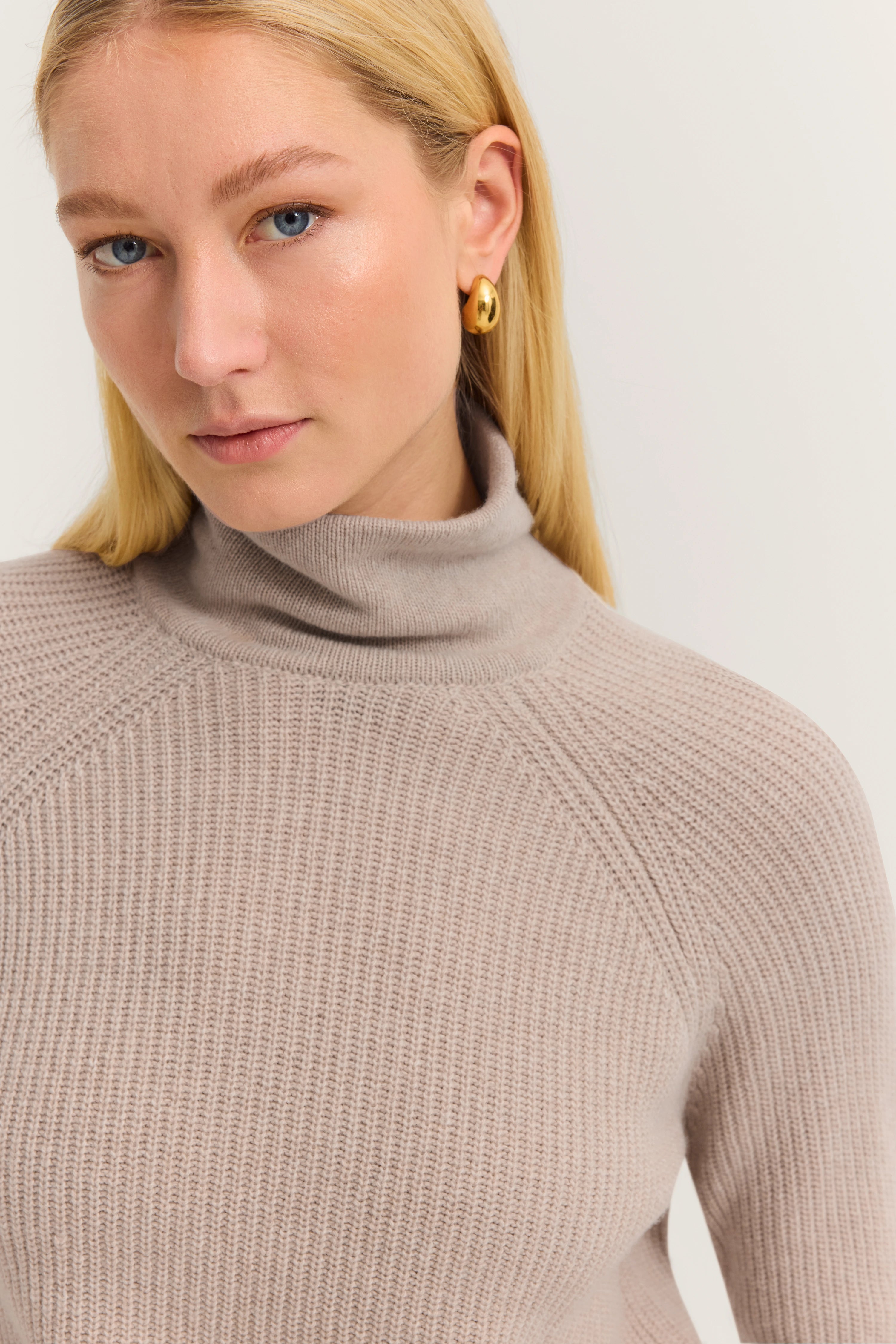 Büstenbild eines Models in einem beige Rollkragenpullover von bugatti, minimalistische Eleganz.