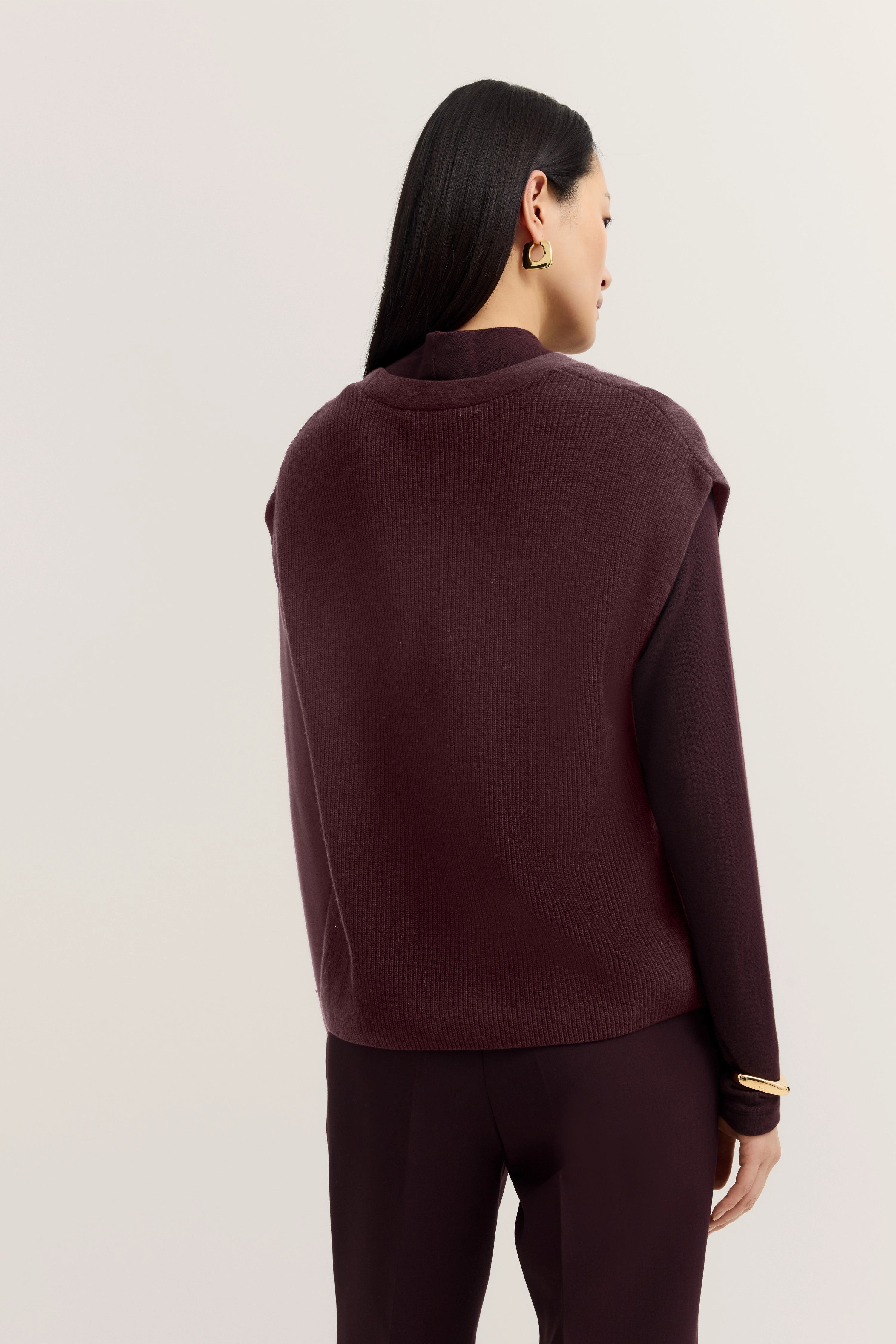 Dunkelrotes bugatti Outfit, Pullover und Hose, Model von hinten, entspannte Pose.