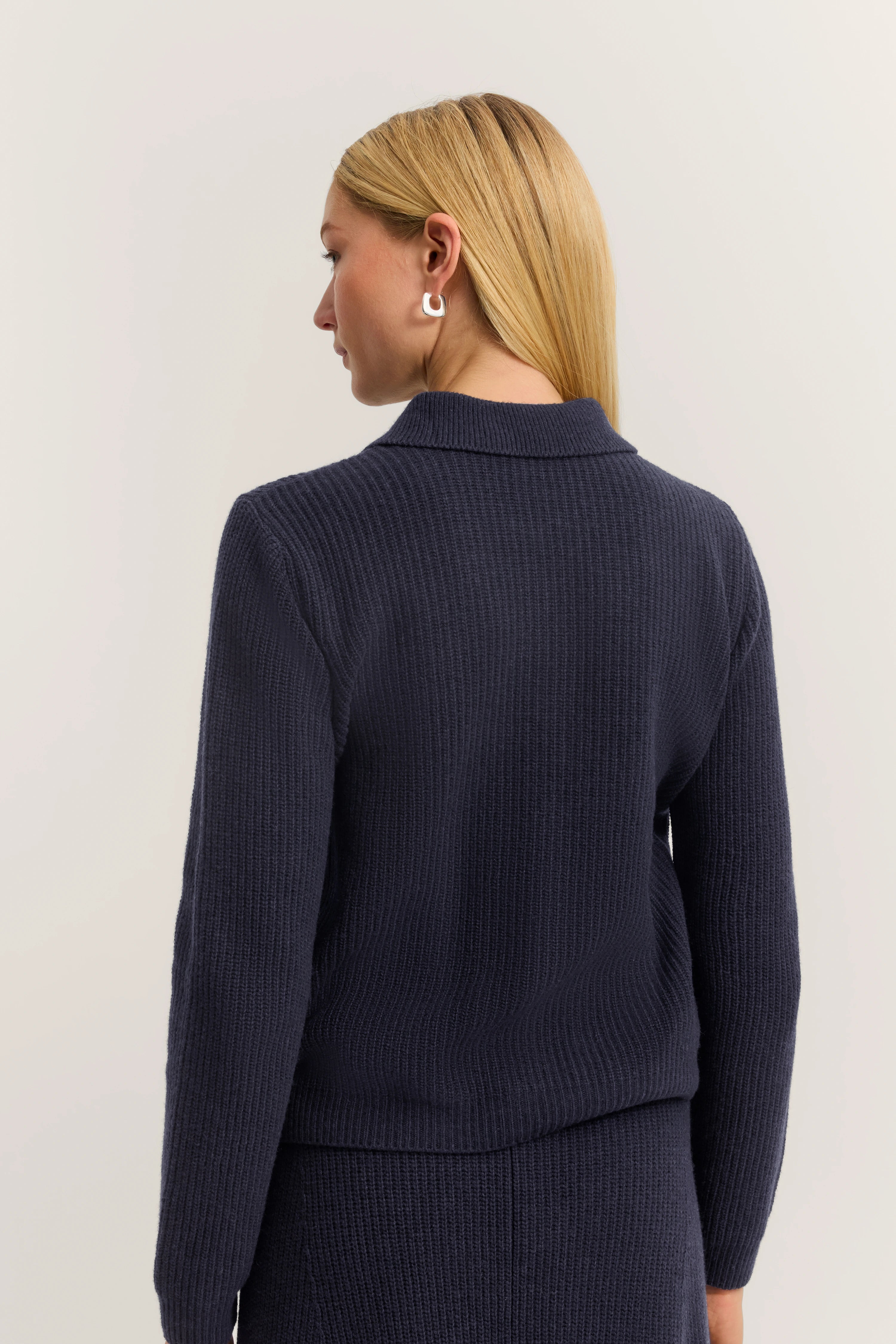 Navy blauer Strickpullover und Rock, Model von hinten, elegantes und zeitloses Design von bugatti.