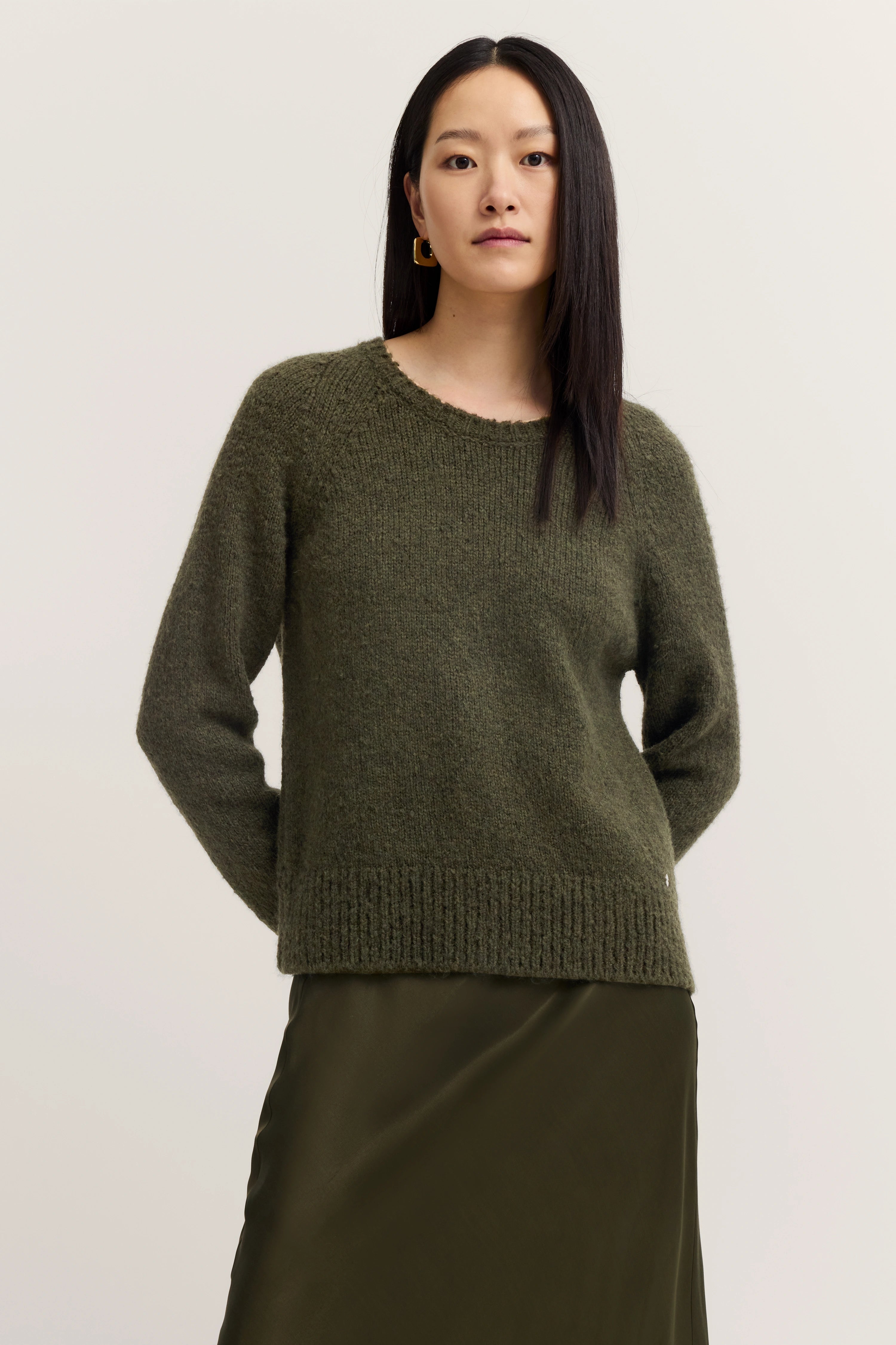 Dunkelgrüner Strickpullover, legeres Modelbild, entspanntes Posing.