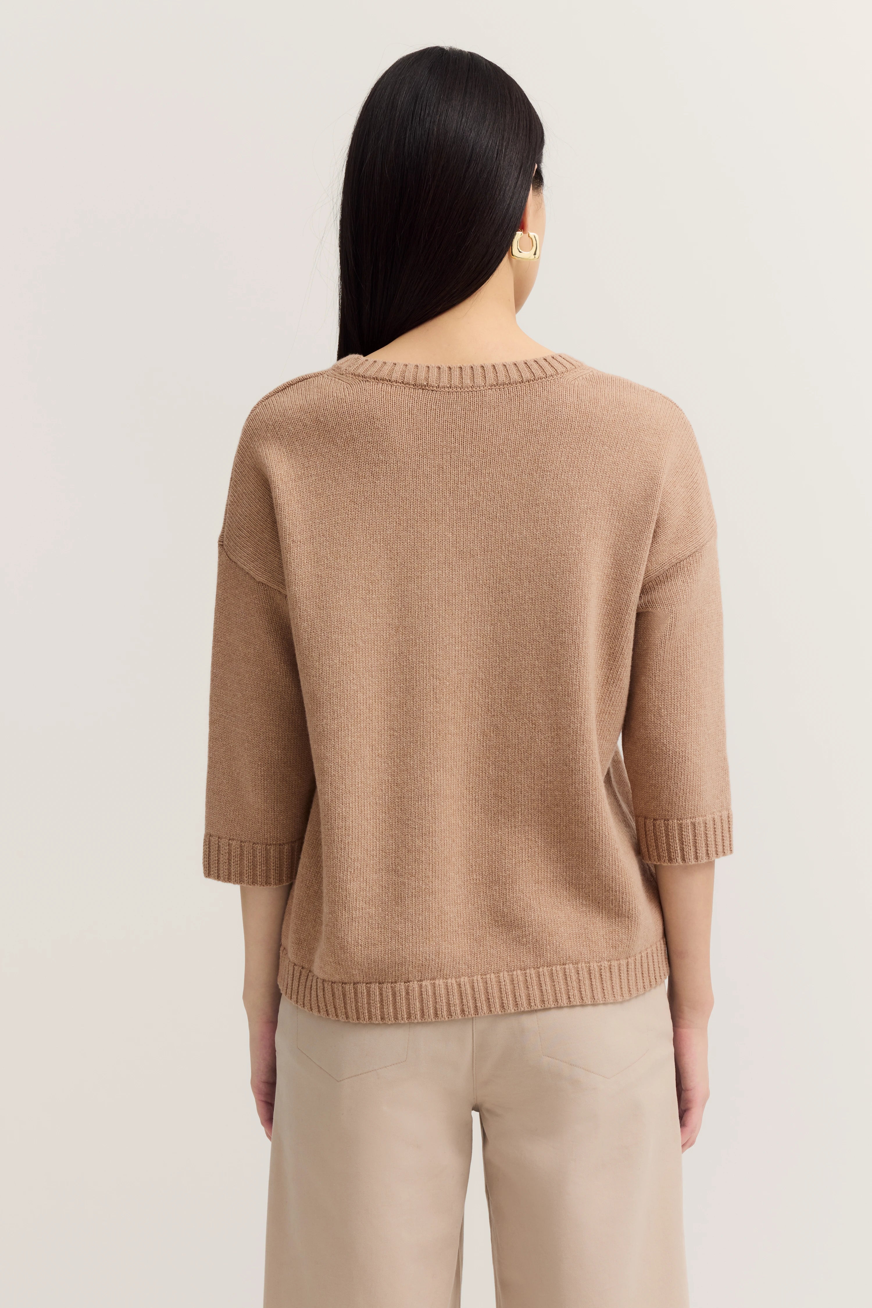 Beigefarbener Pullover und beige Hose, Model von hinten.