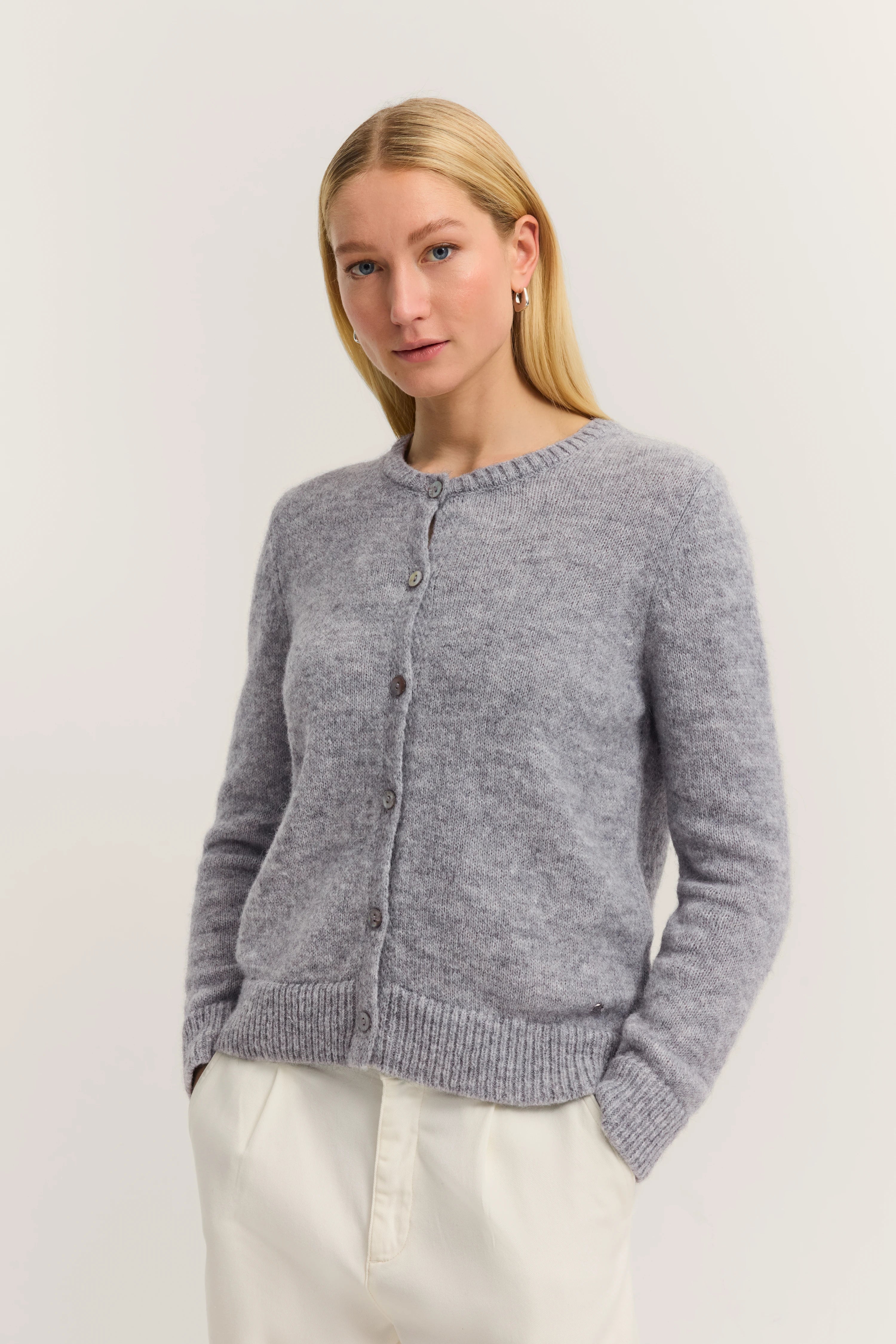 Grauer Cardigan von bugatti, Büstenbild, helles Posing, kombiniert mit weißen Hosen.