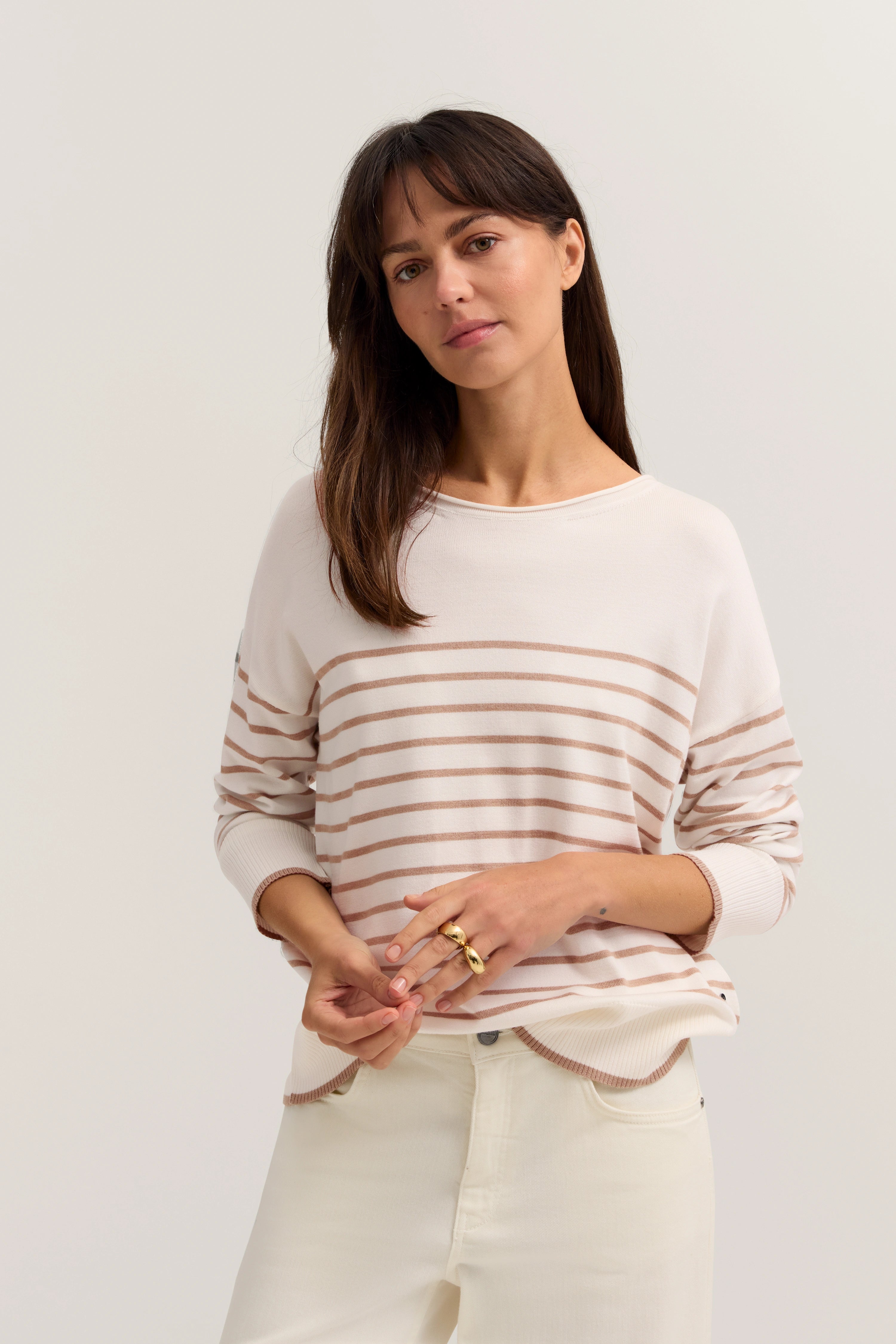 Damenmodell in gestreiftem Pullover in Weiß und Beige, leger posierend, bugatti Stil.