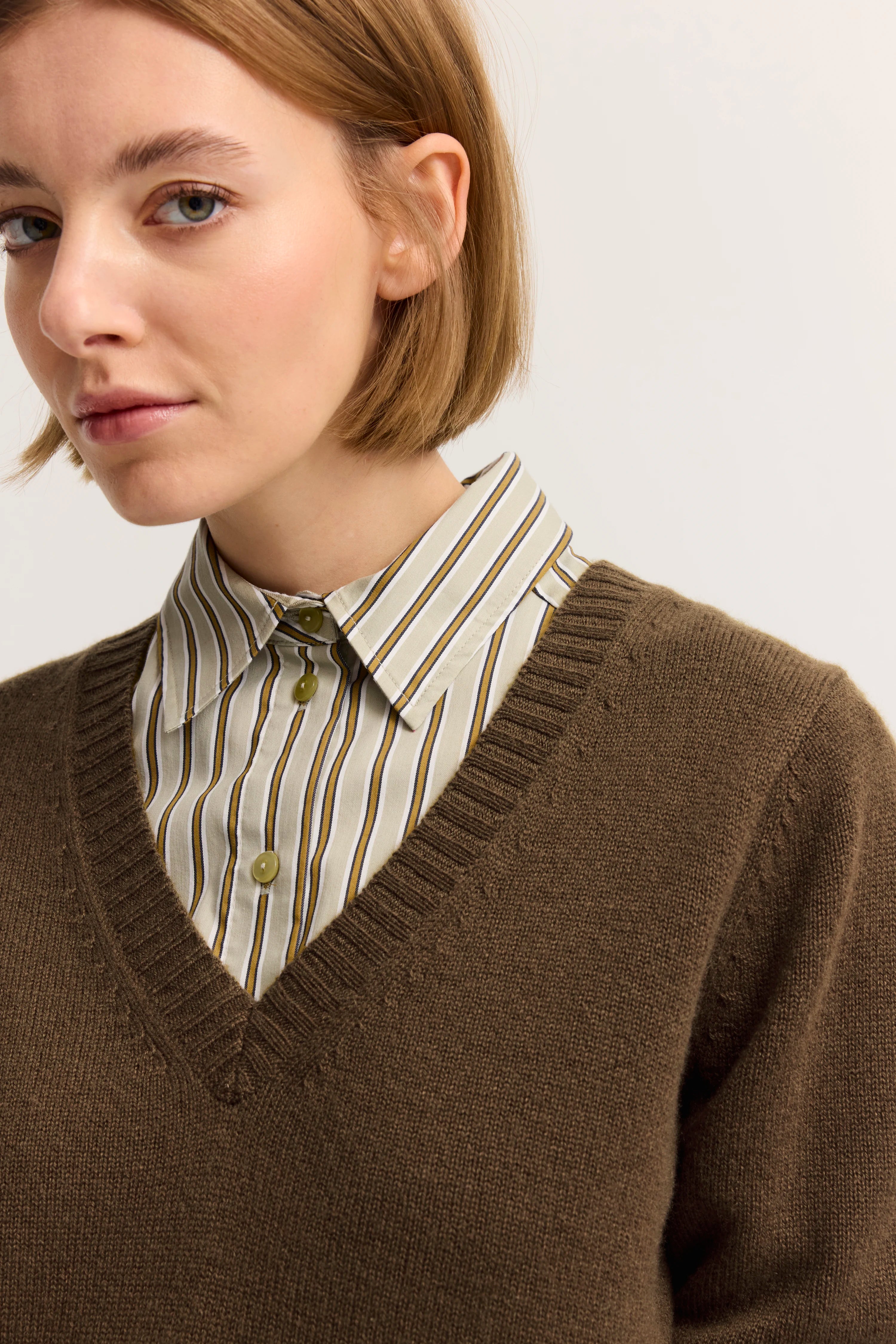 Brauner V-Ausschnitt-Pullover über gestreiftem Hemd, Büstenbild, bugatti Stil.