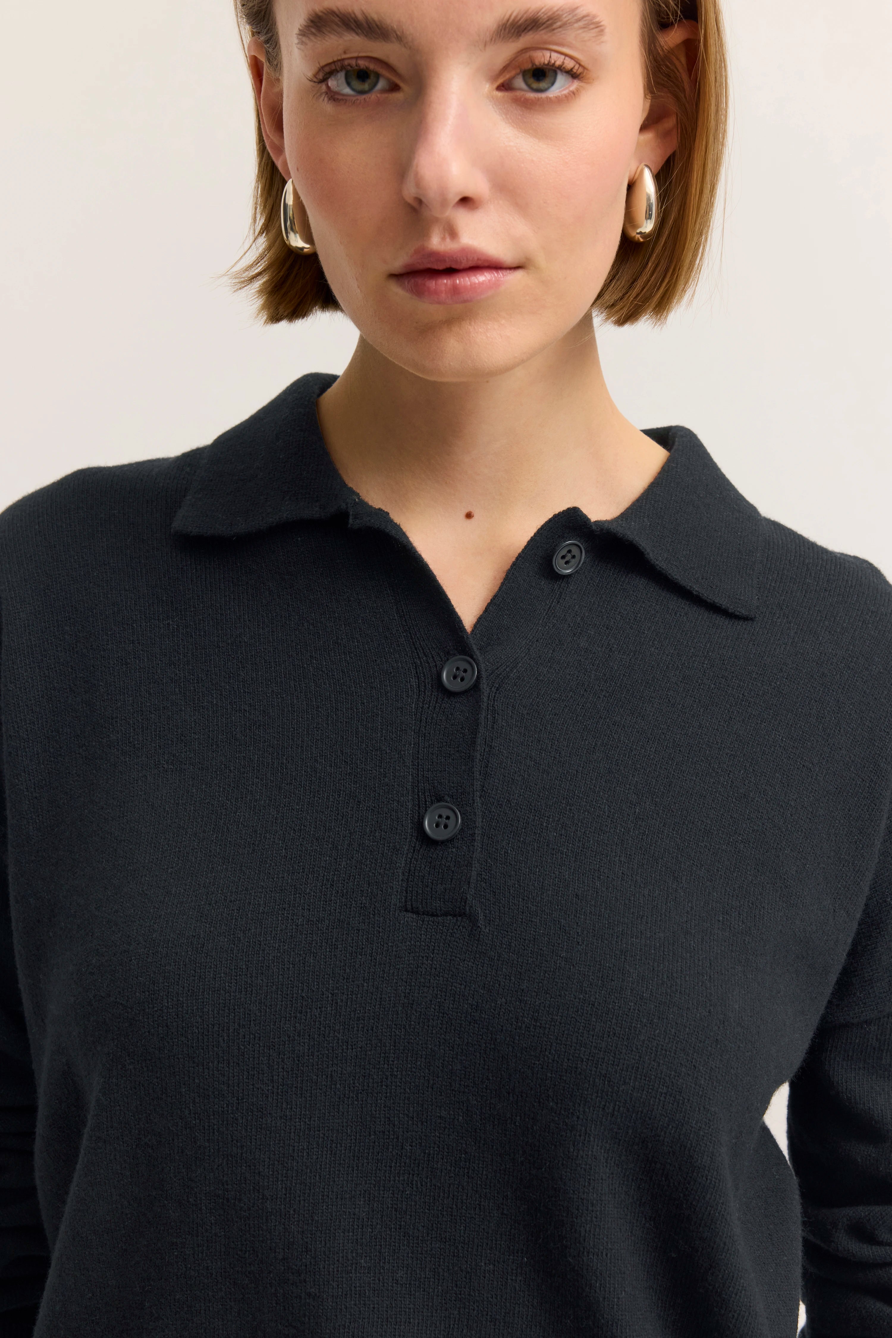 Büstenbild von Frau in schwarzem bugatti-Pullover mit Knopfleiste und Kragen.