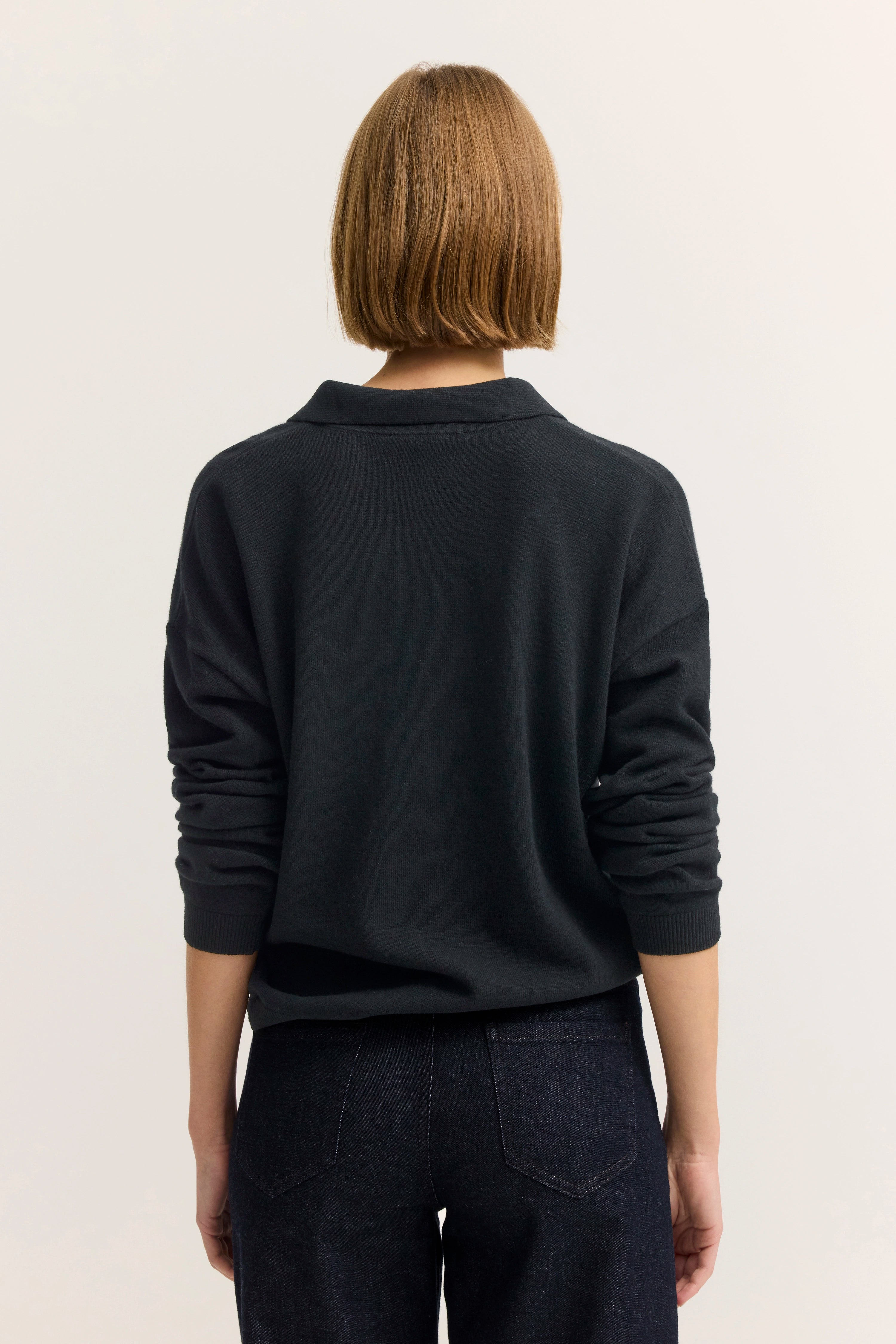 Büstenbild mit schwarzem bugatti Pullover und dunkler Jeans, Rückansicht.