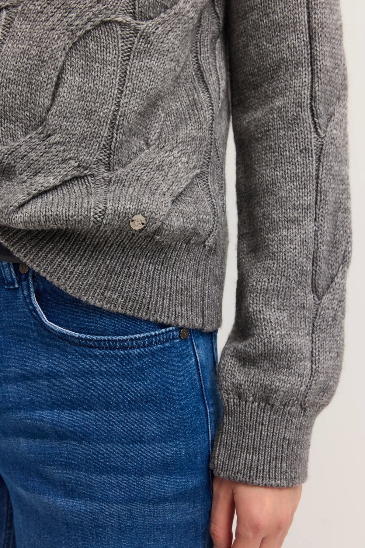 Grauer Strickpullover und blaue Jeans, Detailaufnahme.