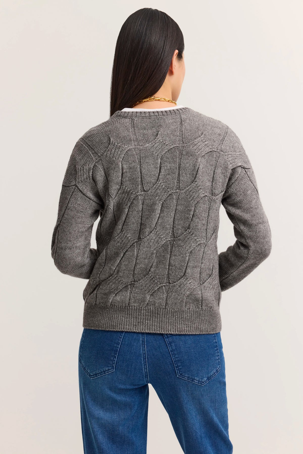 Grauer Zopfpullover von bugatti, kombiniert mit blauen Jeans. Rückansicht eines Models.