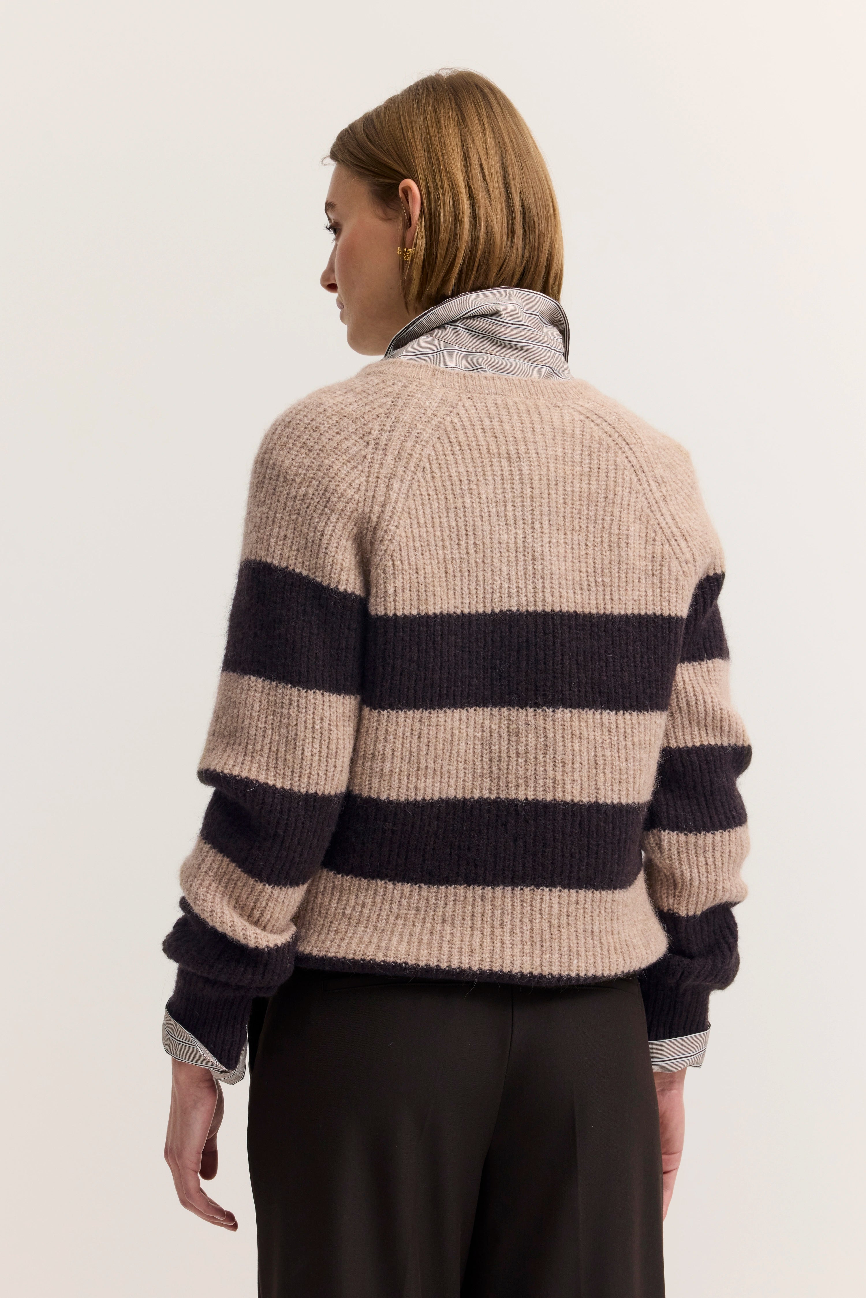 Beiger und schwarzer gestreifter Pullover, Hemdkragen, Model von hinten, casual chic Look.