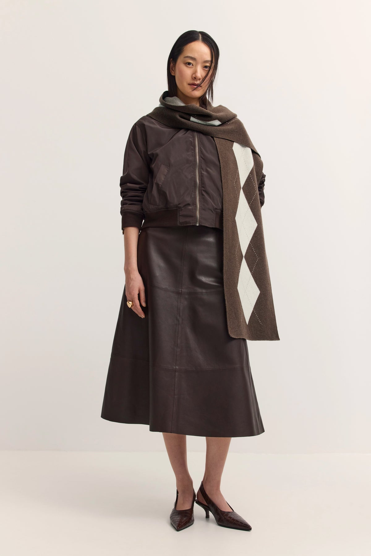 Dame in brauner Jacke, Lederrock, Schal mit Rautenmuster