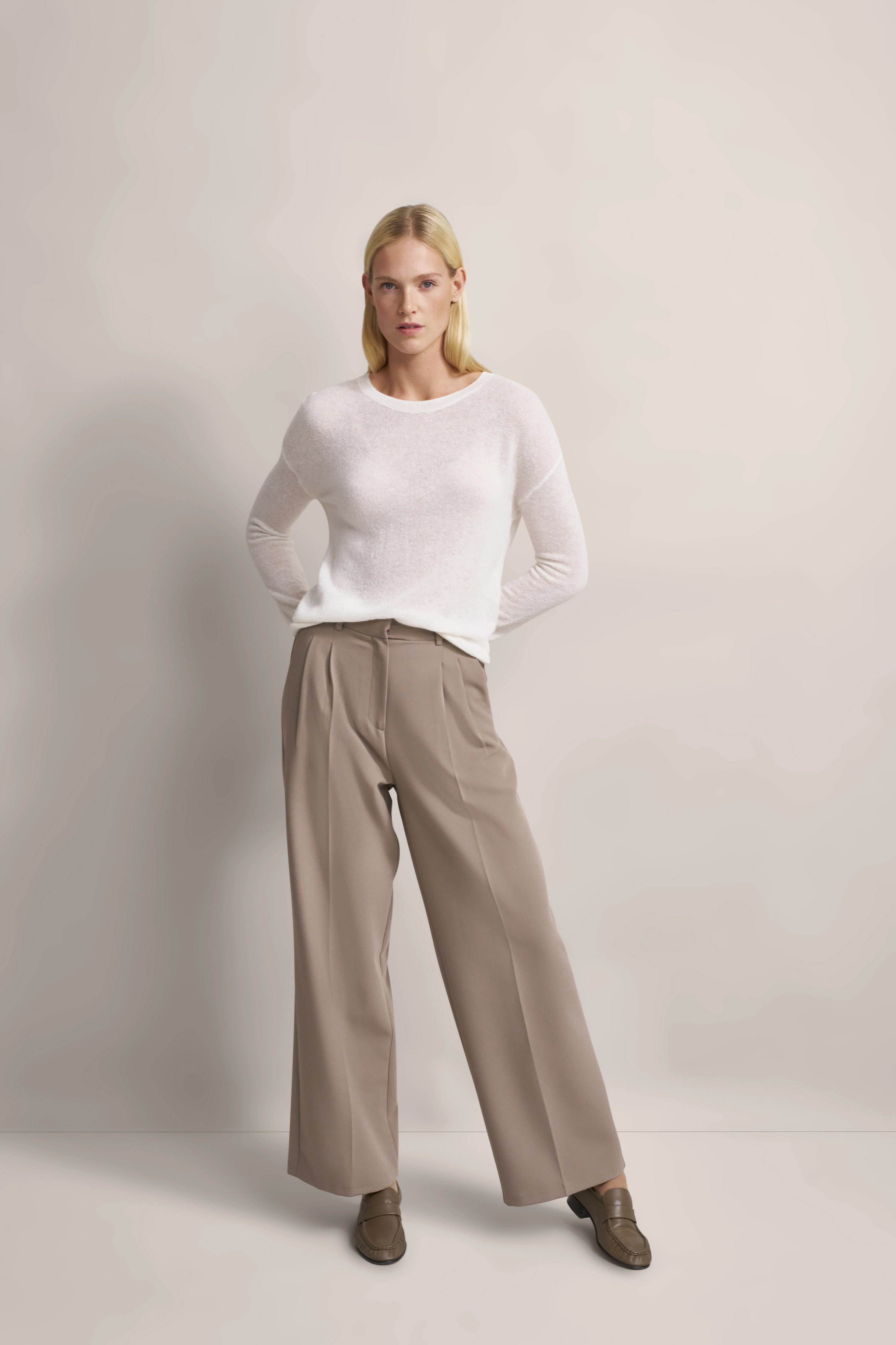 Model in weißem Pullover, beige Hose, entspanntes Posing, bugatti Stil und Eleganz.