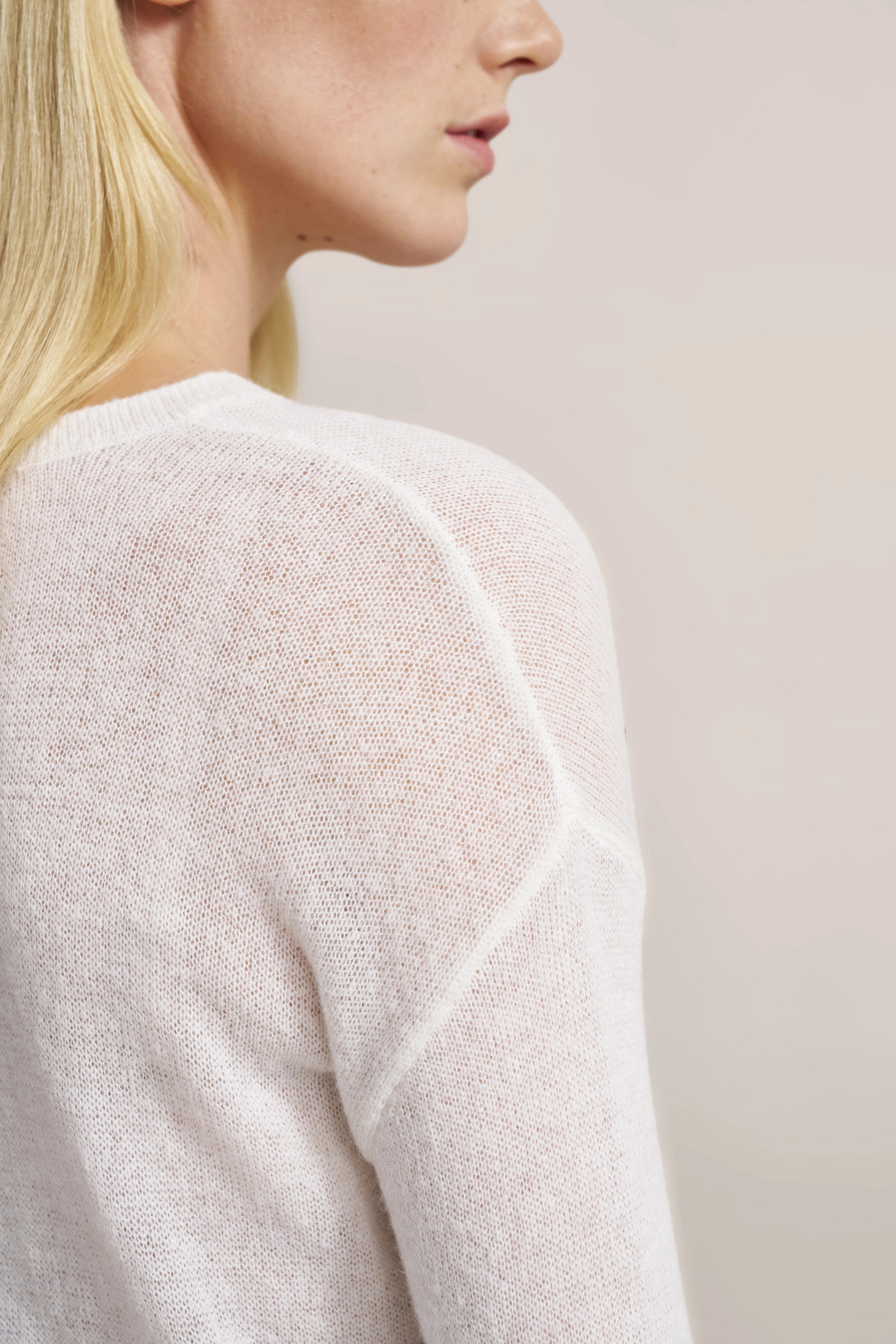 Büstenbild eines Models in weißem, leicht transparentem Strickpullover von bugatti.