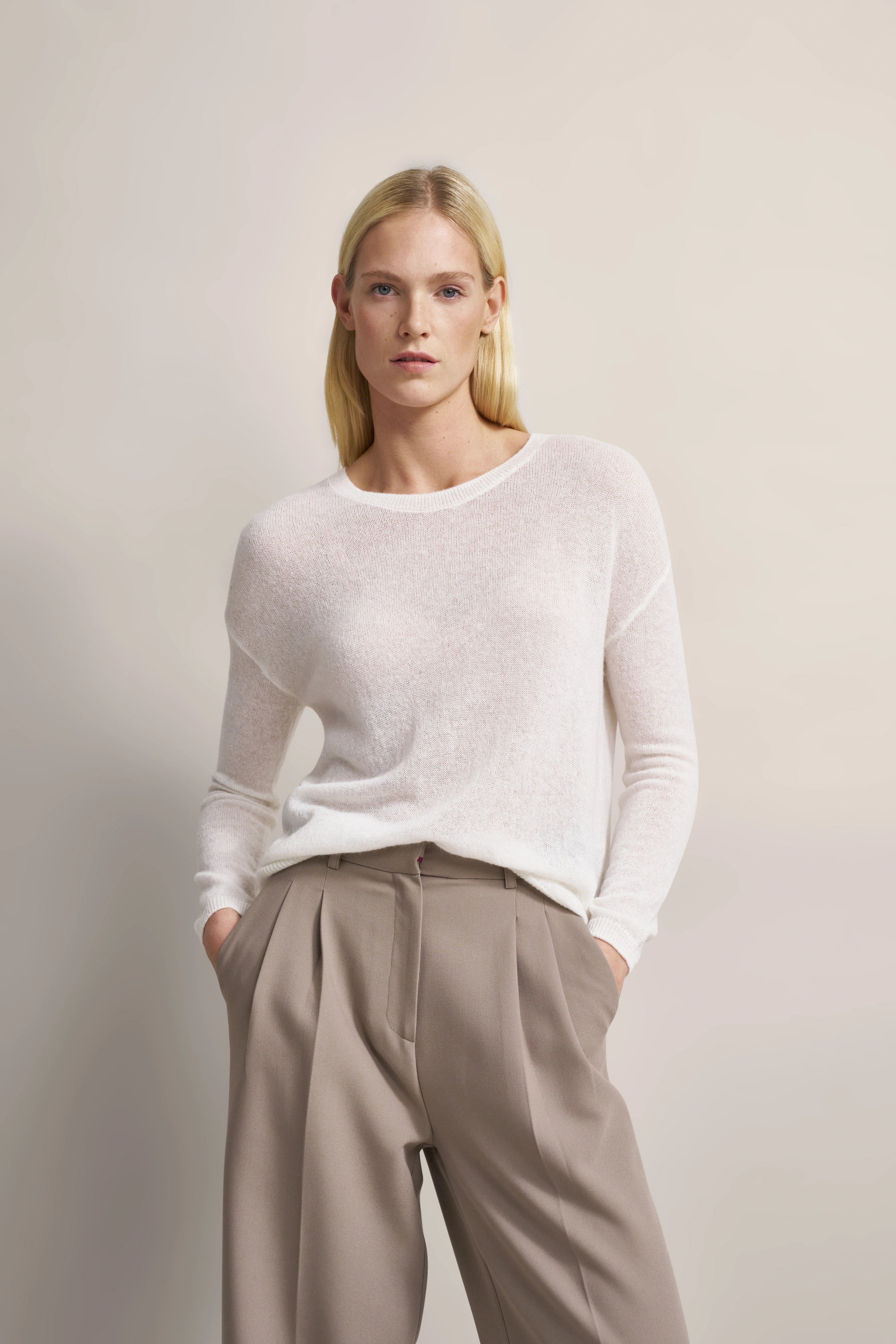 Weißer Pullover und beige Hose von bugatti, Modelbild, lässige Pose mit Händen in den Taschen.