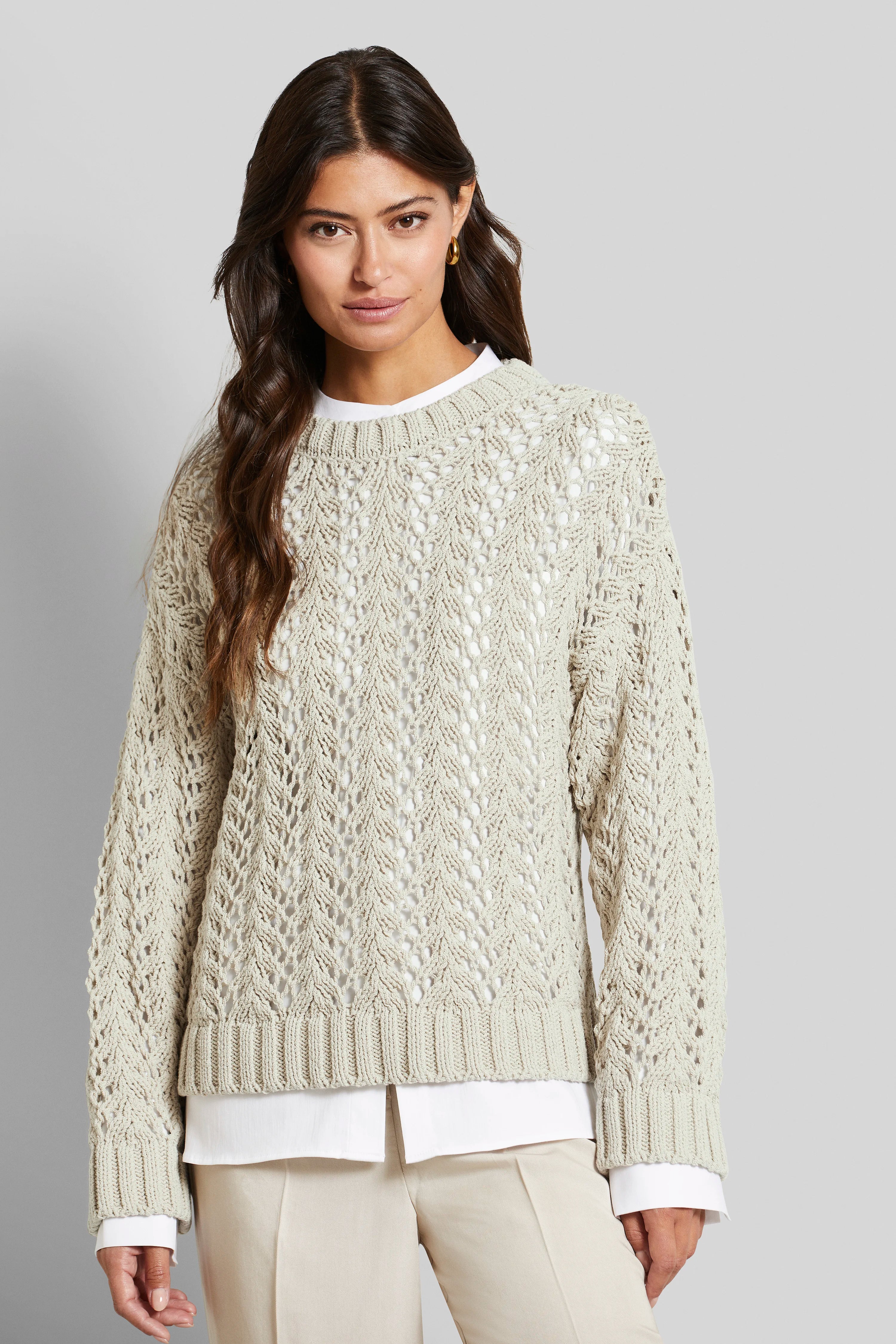 Damesmodel in crèmekleurige trui en beige broek, frontaal poserend.