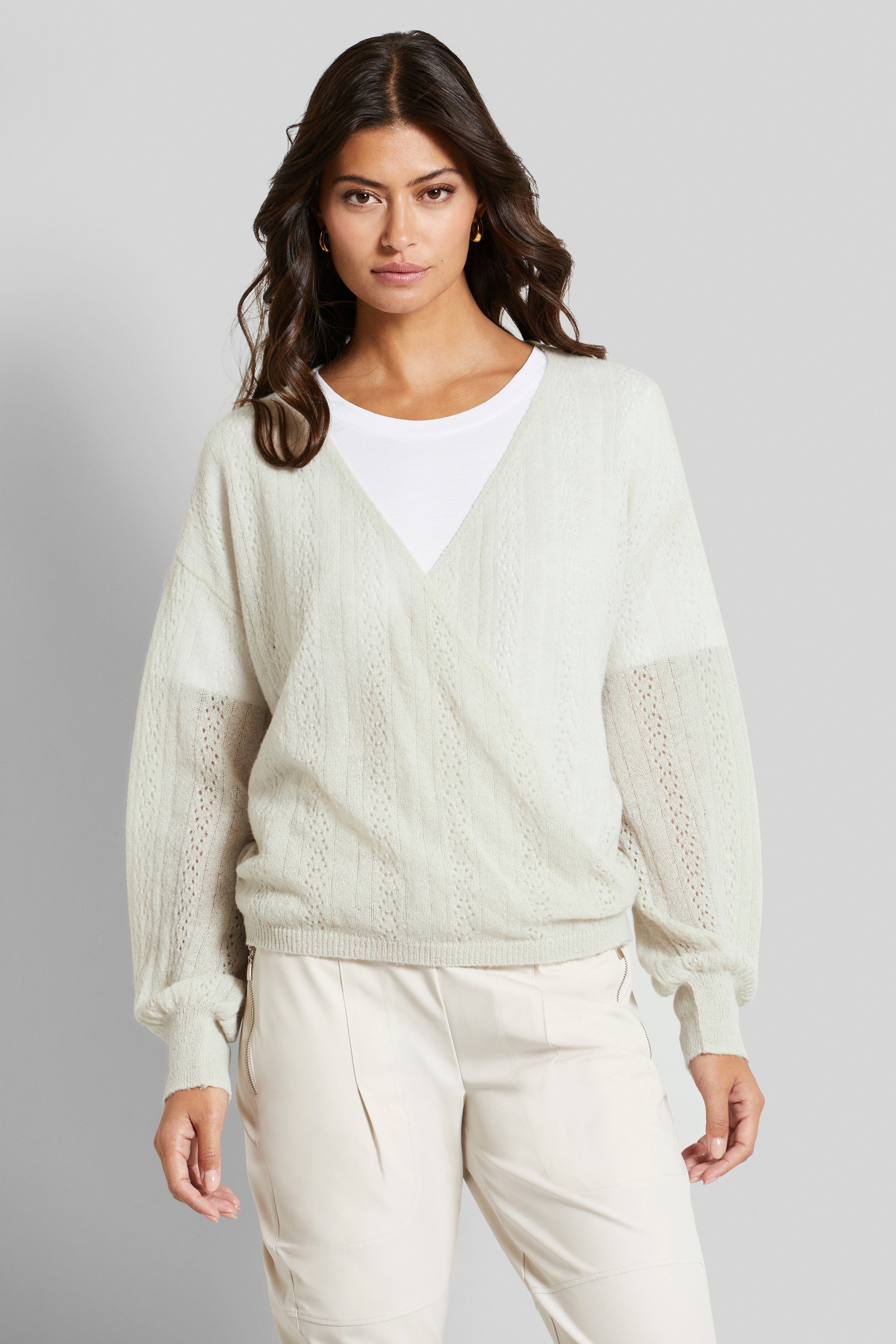 Modelbeeld: Vrouw draagt crèmekleurige trui en witte blouse van bugatti, ontspannen pose.
