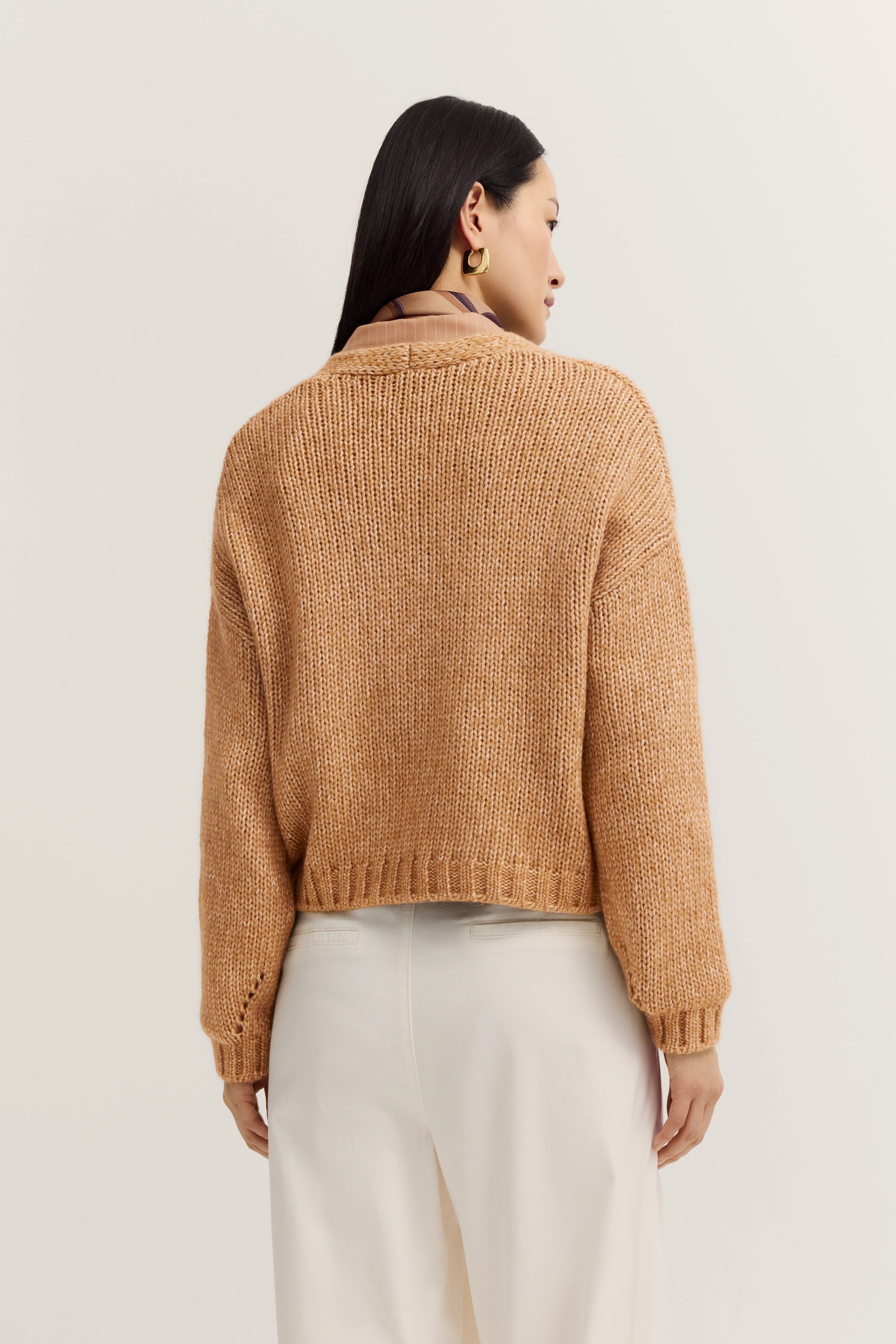 Beiger Strickpullover von hinten, kombiniert mit weißer Hose, Modelbild von hinten.