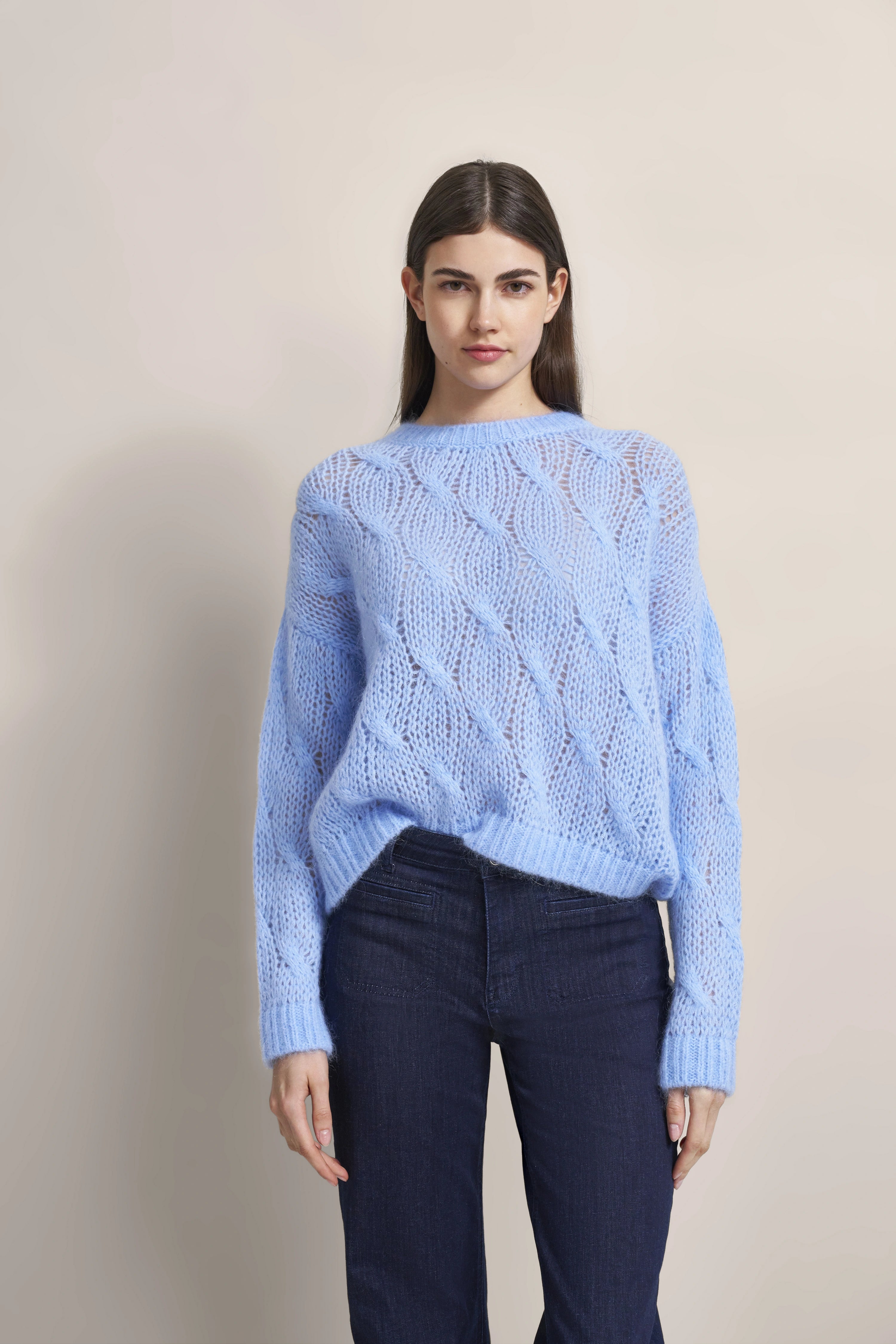 Blauer Strickpullover und dunkle Jeans, Modelbild, entspanntes Posing.
