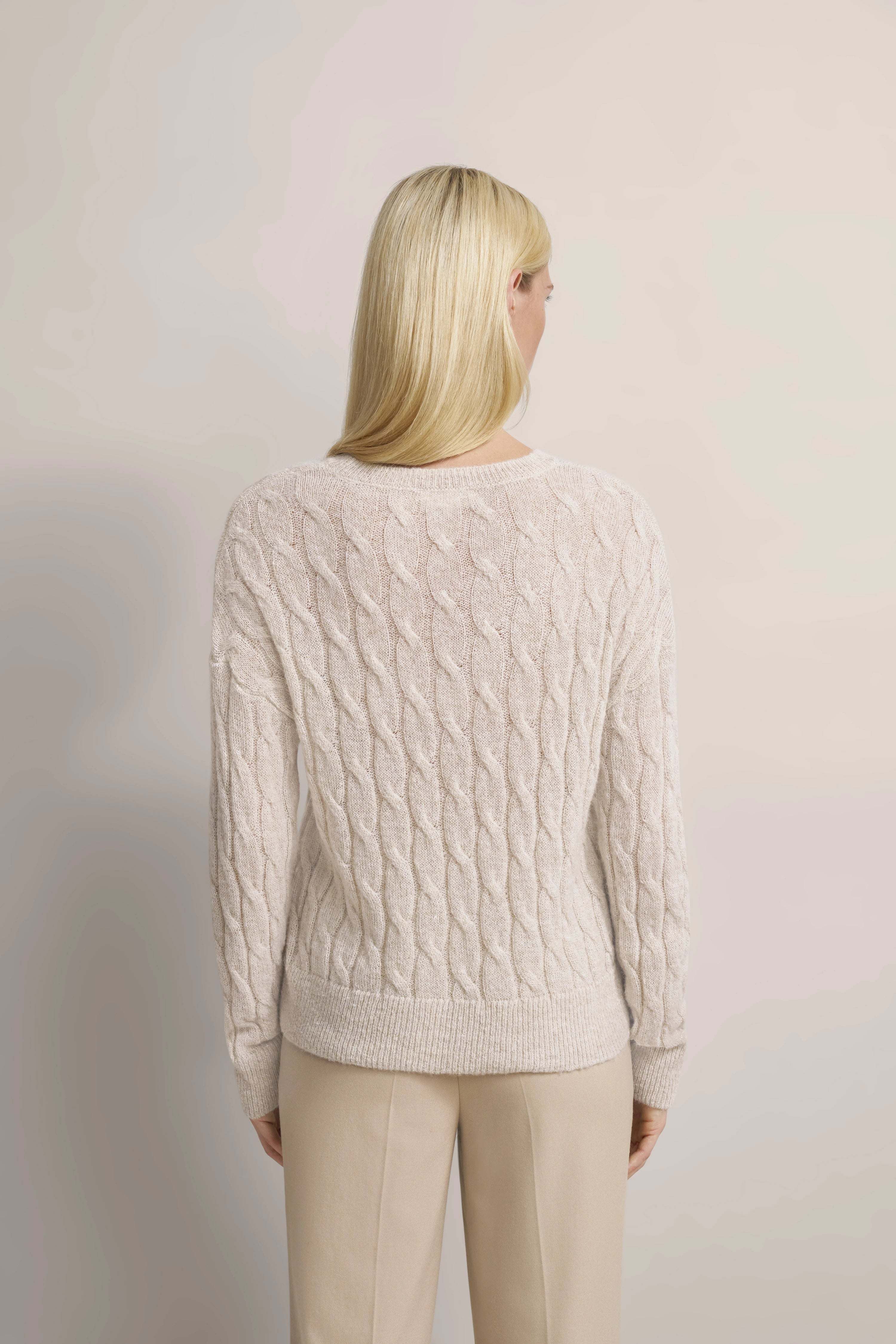 Beiger Zopfstrickpullover und cremefarbene Hose, Rückansicht, legeres Modelbild.