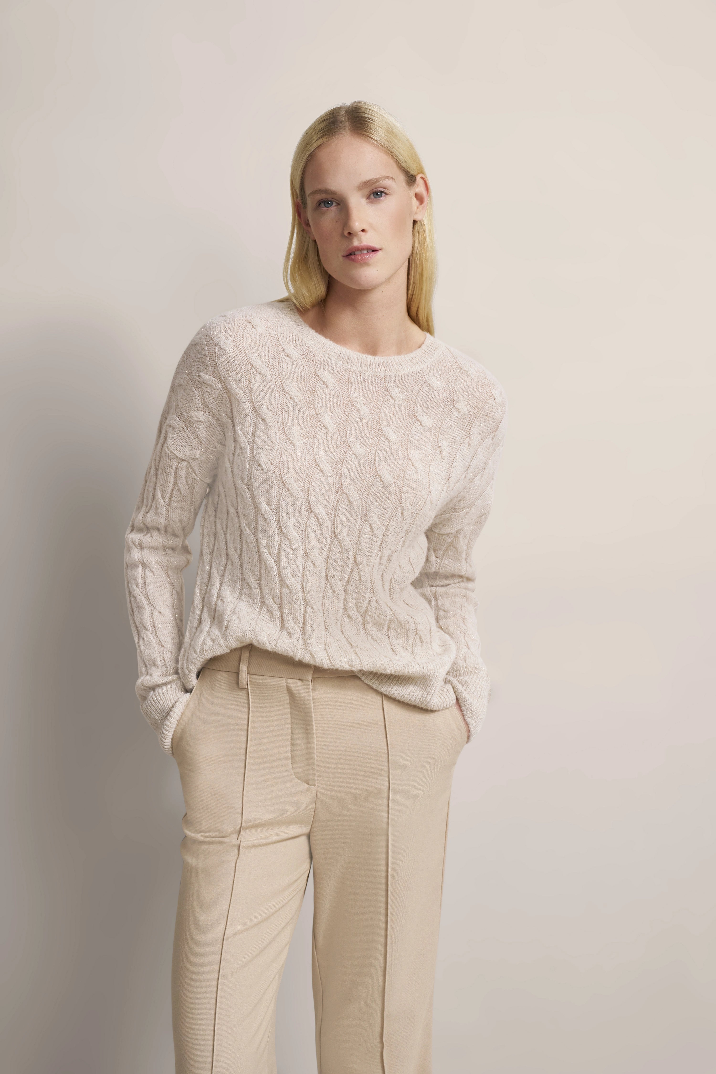 Beiger Zopfpullover und beige Hose, Modelbild mit lässigem Posing, bugatti Stil.