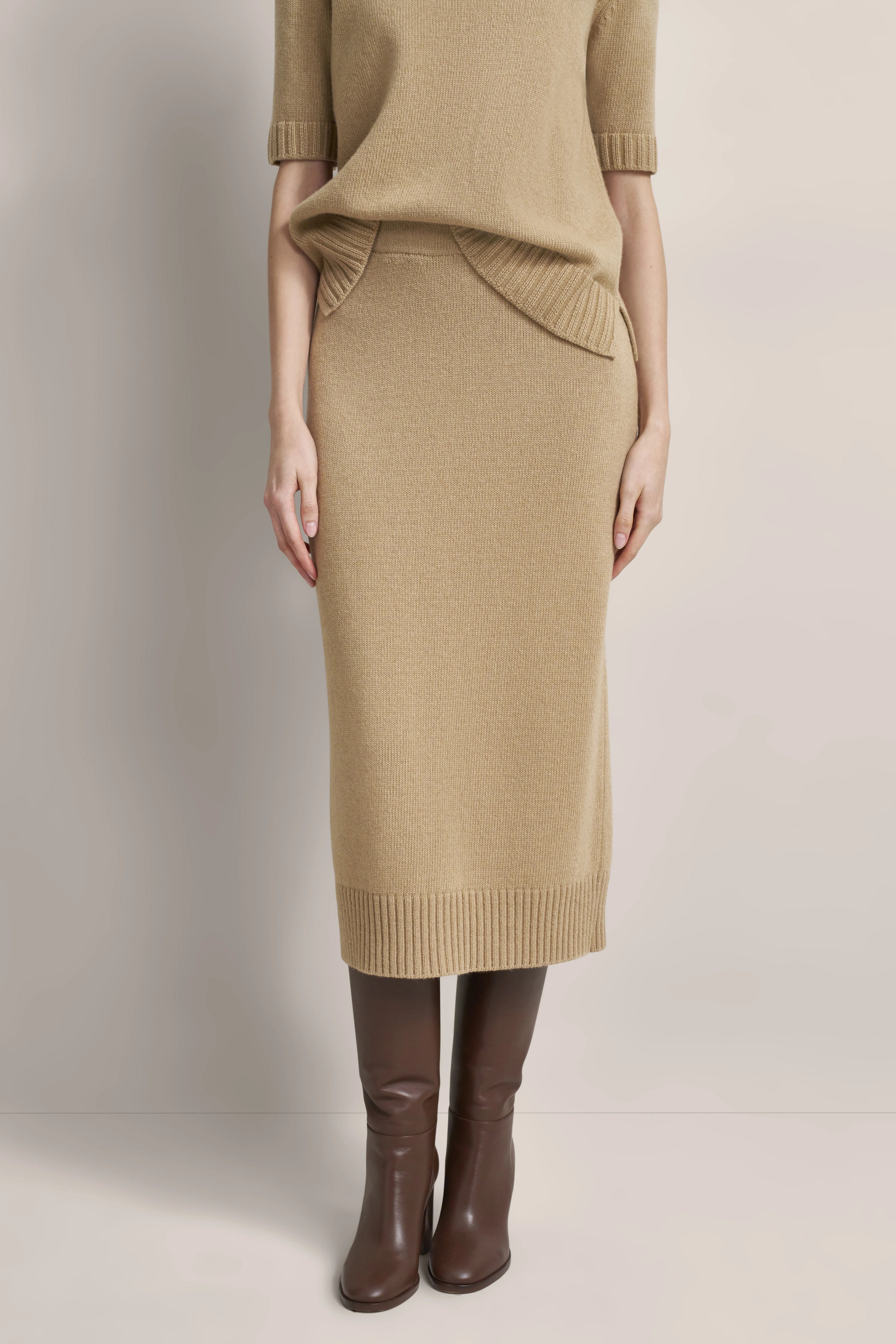 Beiges Strick-Kleid mit kurzen Ärmeln, braune Stiefel, legeres Modelbild von bugatti.