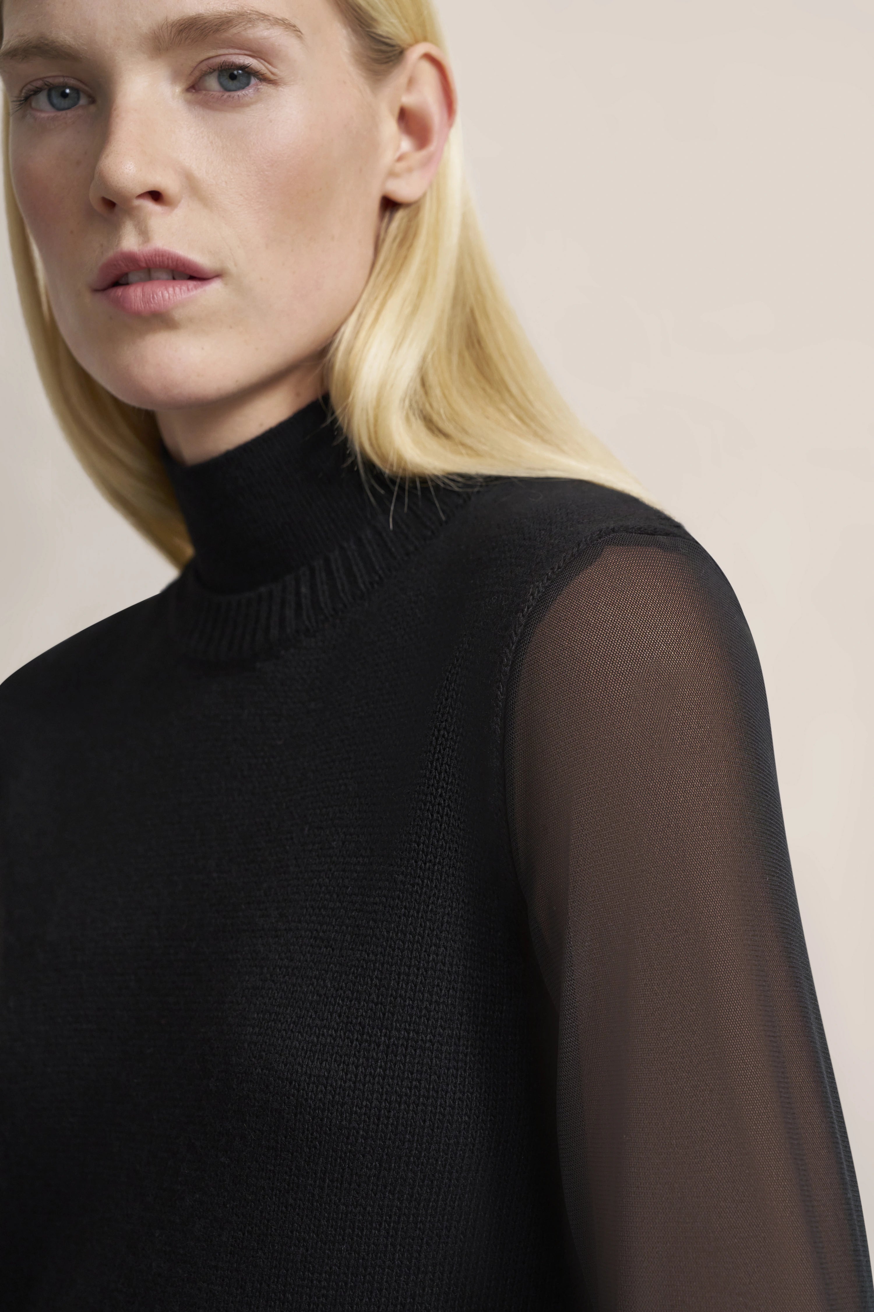 Schwarzer bugatti Rollkragenpullover mit transparenten Ärmeln, Modelbild, elegantes Posing.